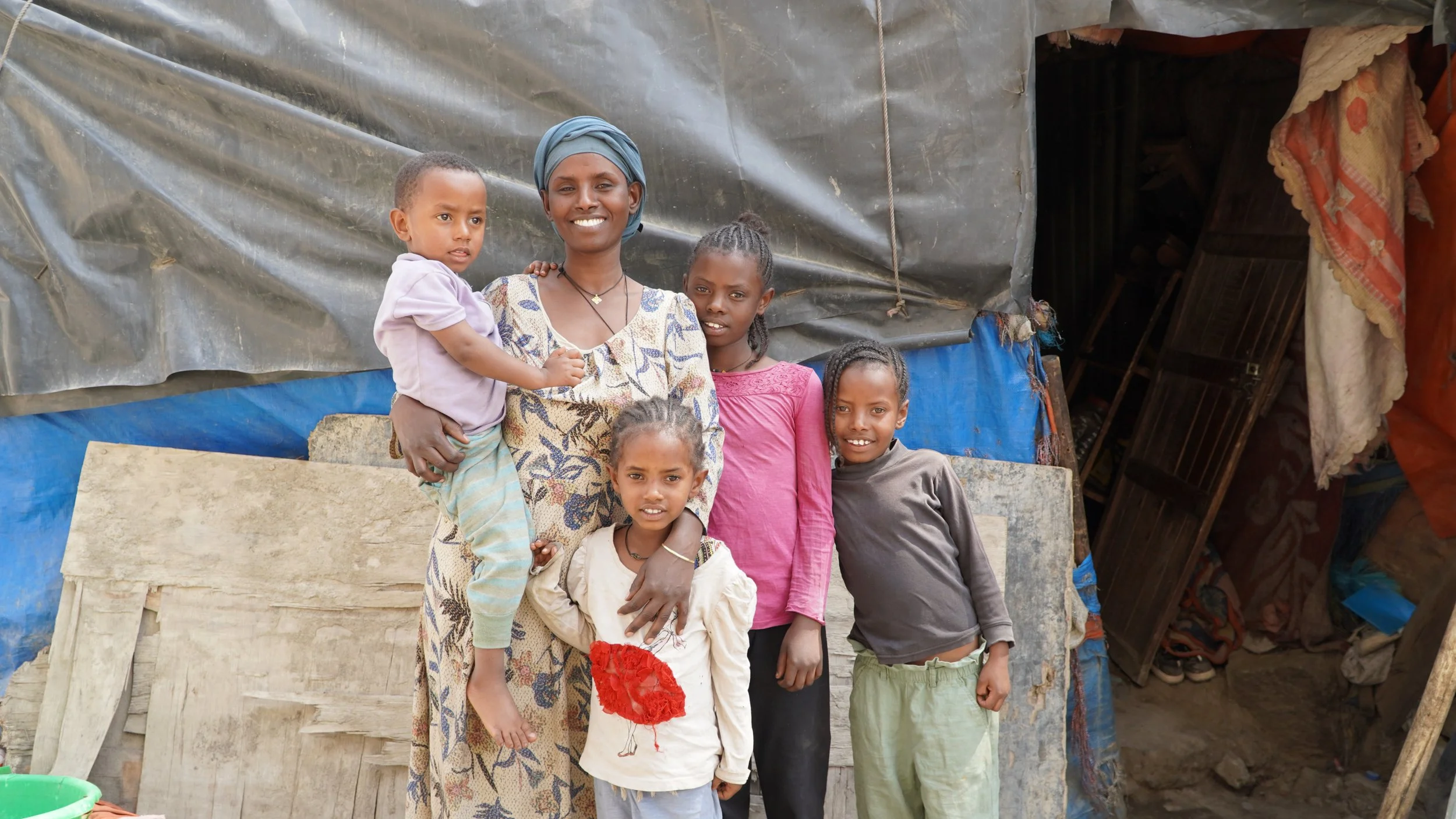 A young mother smiling with her three little girls and holding her baby boy