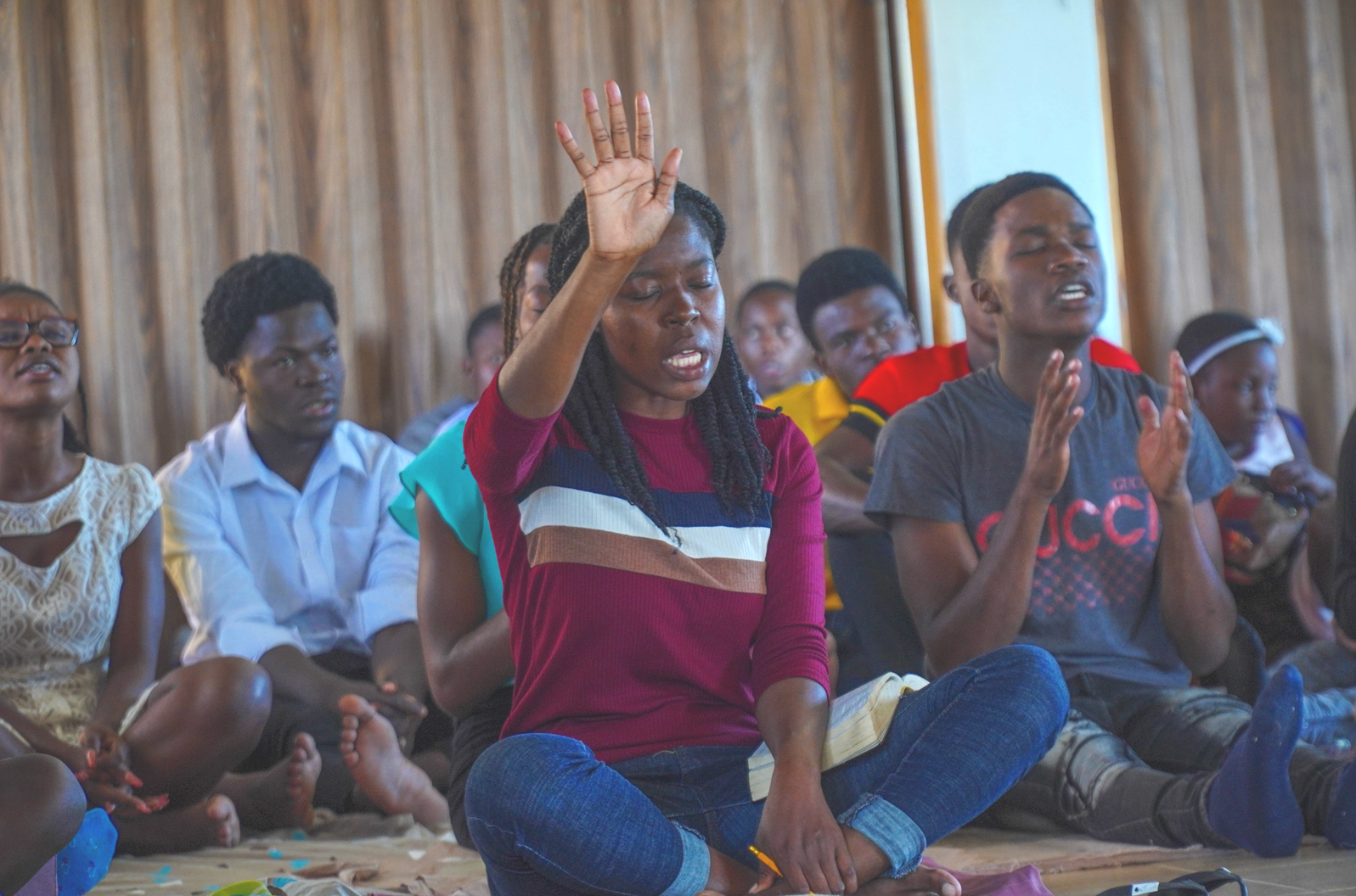 Group of young men and women praying together with hands lifted high
