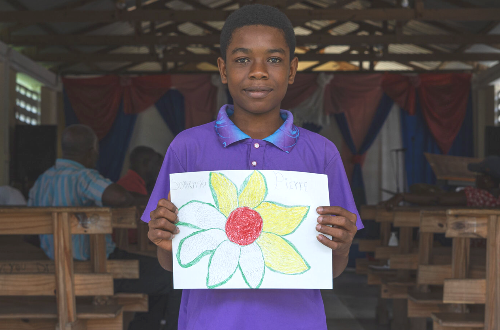 Young boy holding up an interact flower drawing he made