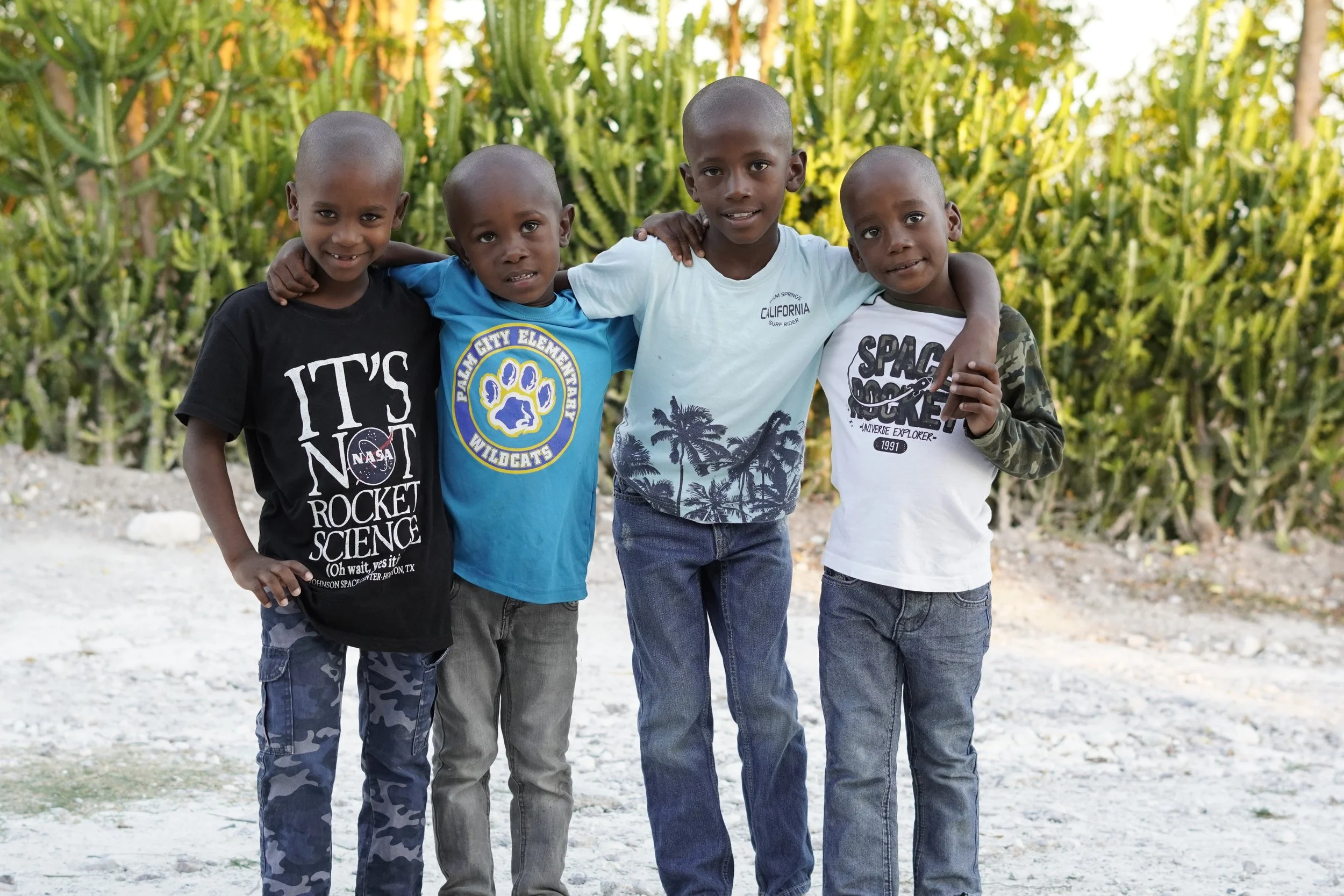 Four little brothers smile with their arms around each other