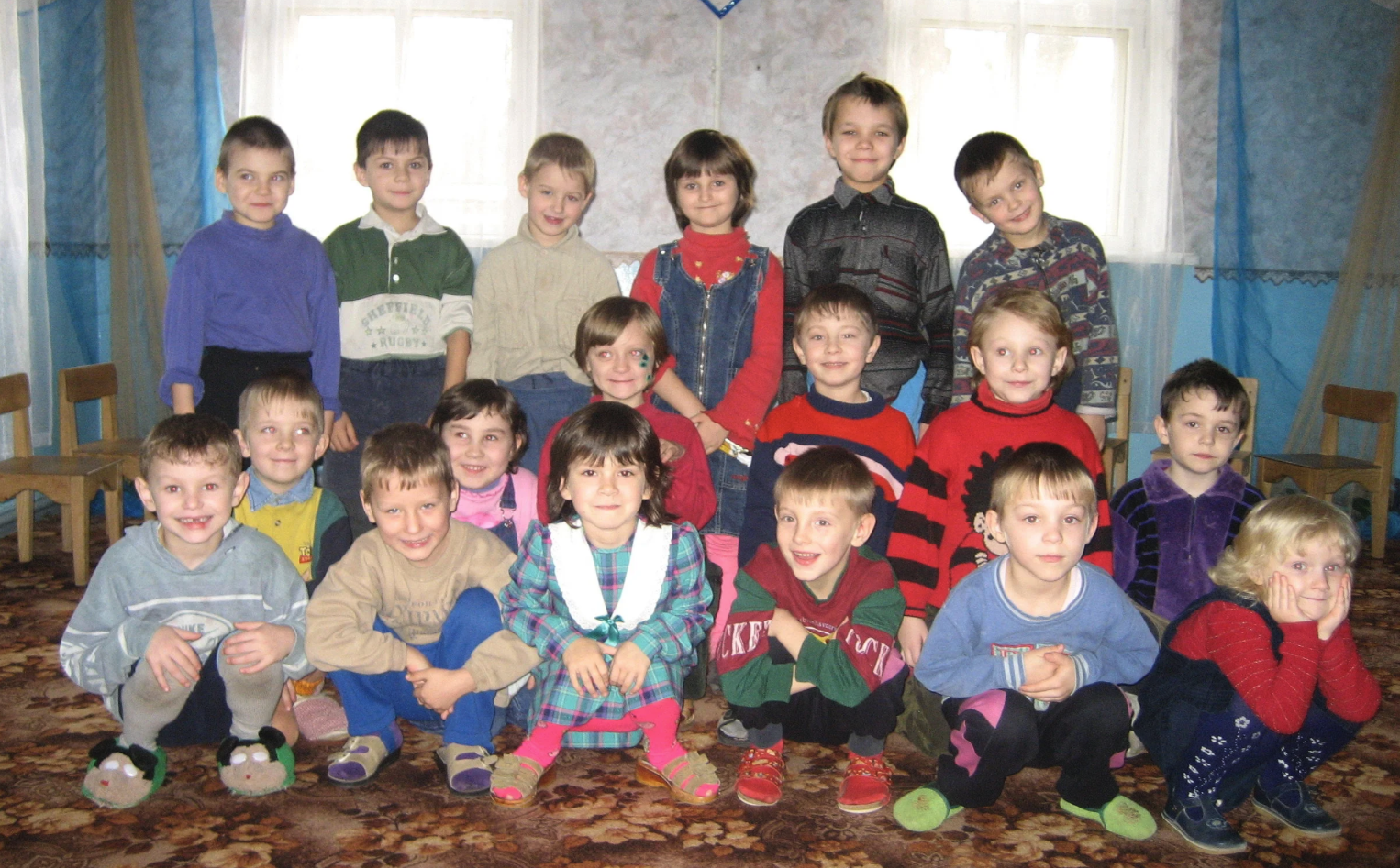 A group of Ukrainian children smile as a group inside a home