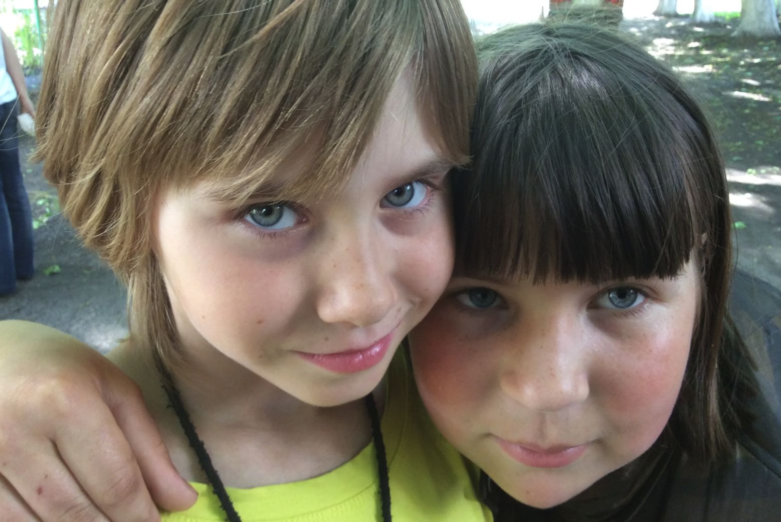 Two Ukrainian girls hugging and smiling at a park