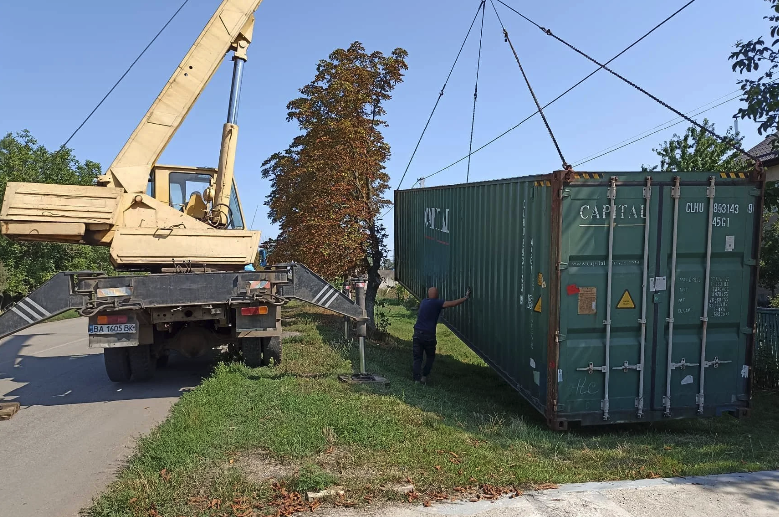 A shipping container is set down outside by a crane