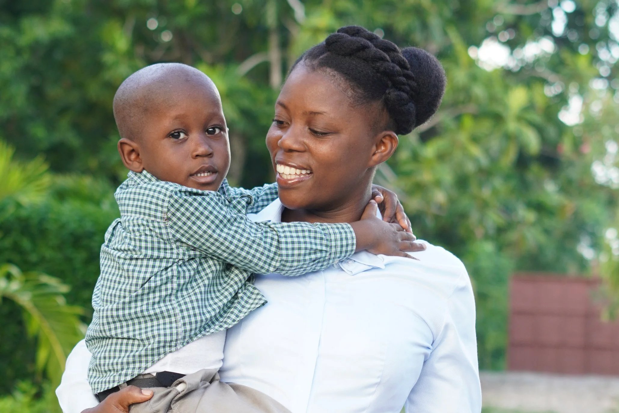 Haitian mother smiling at her little son who she is holding outside