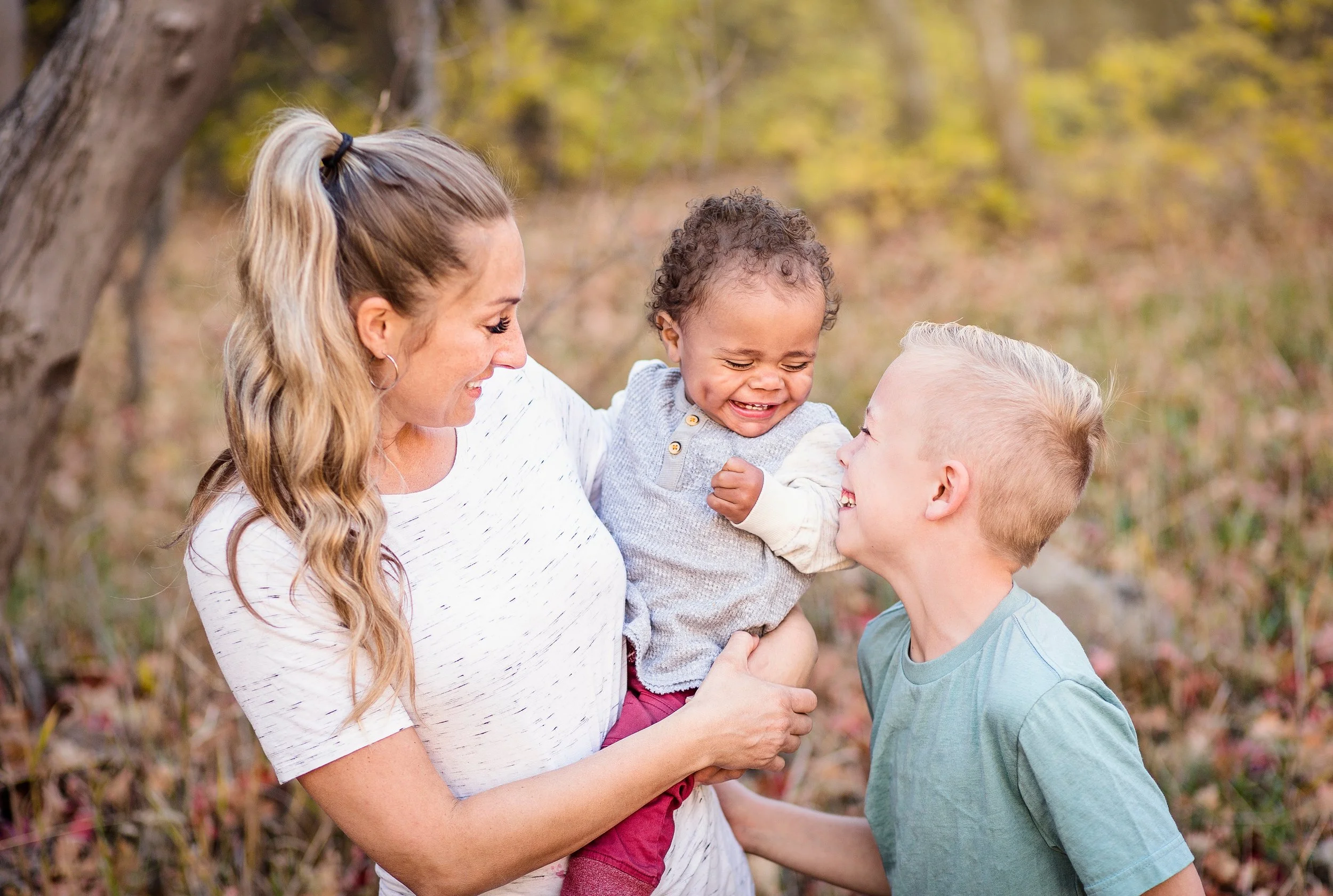 An American mother holds her adopted baby boy who is laughing with her older brother.