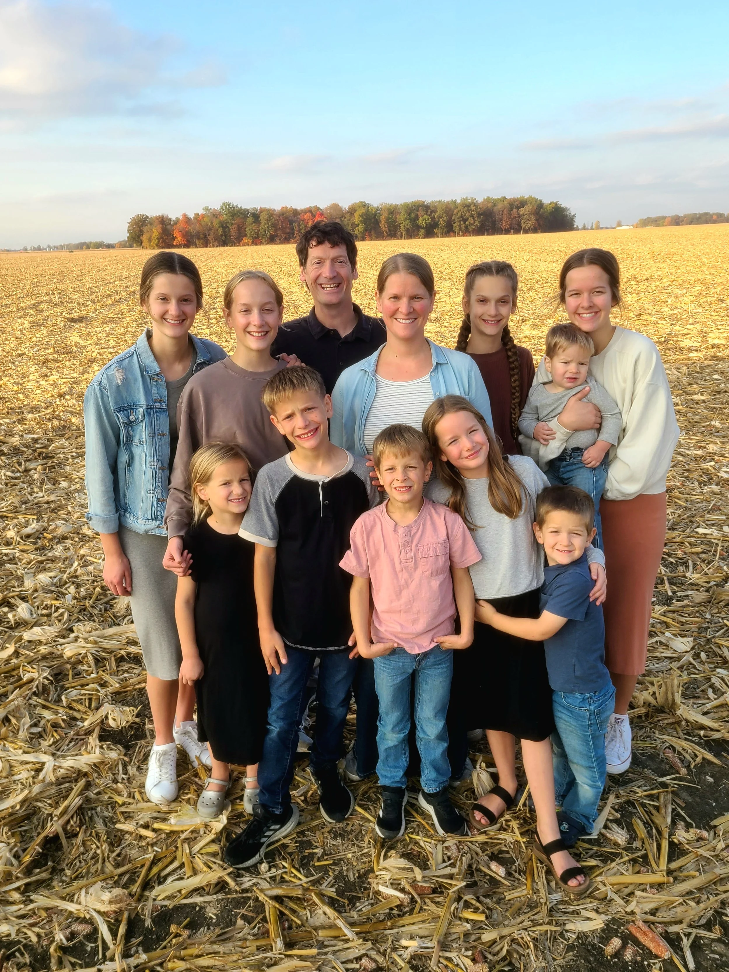 Matt and Tiffany with their ten children smiling and standing in a field together