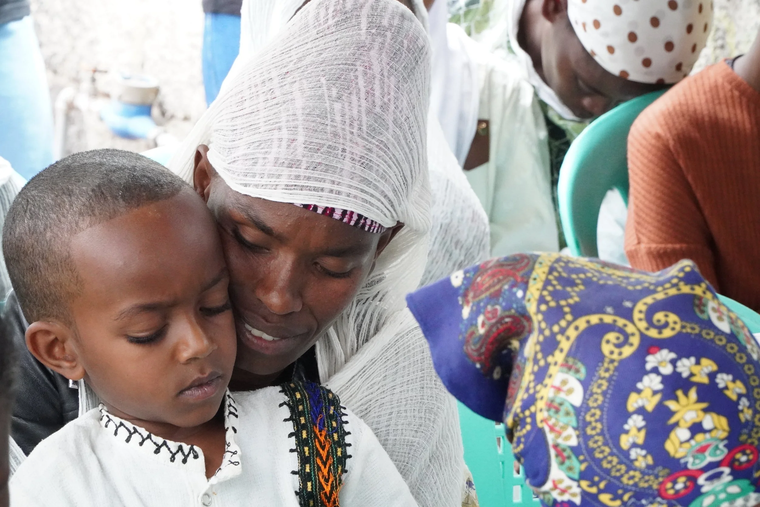 A mother holding her little son and praying with him