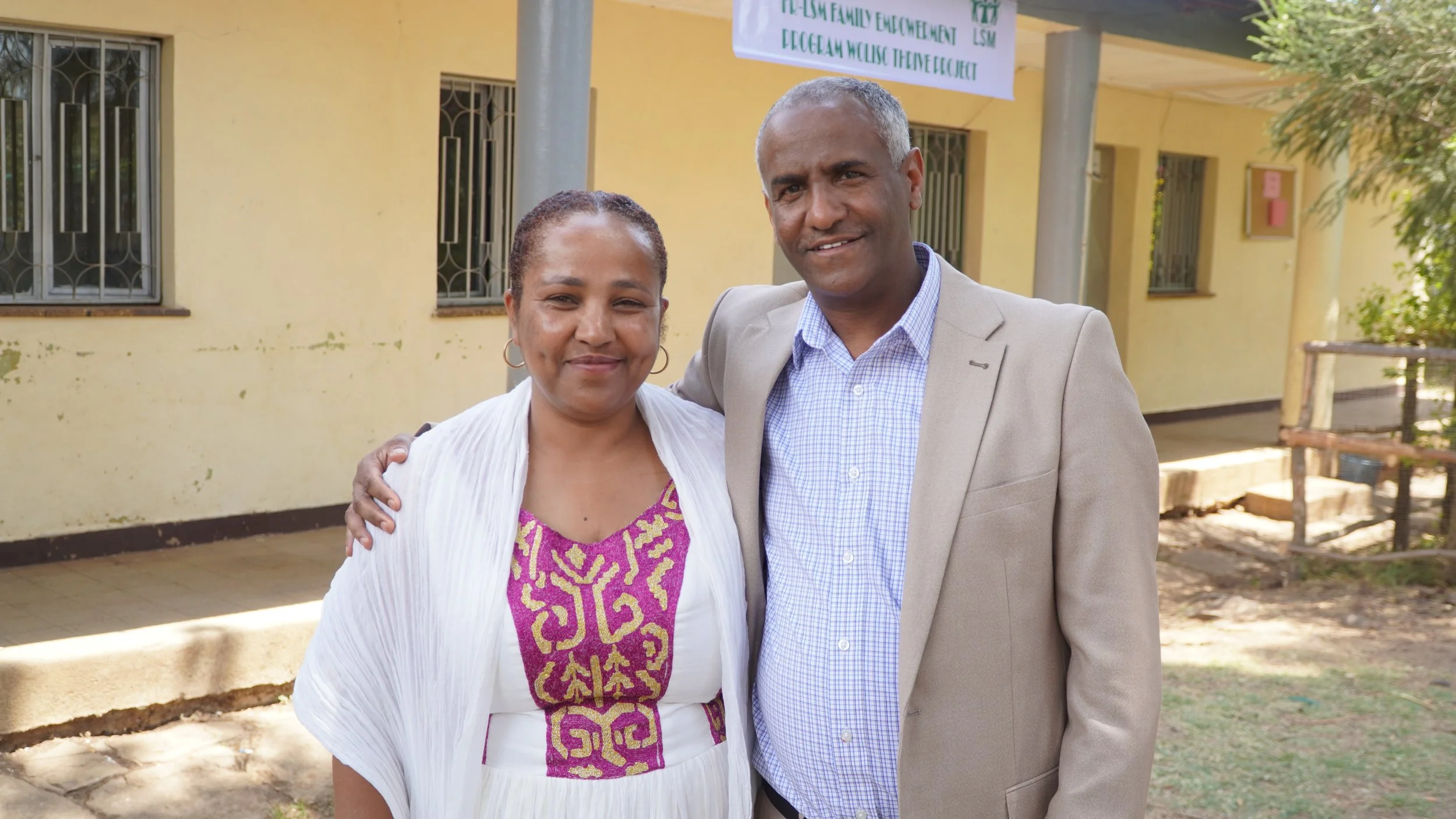 Ethiopian couple Johney and Mekdes smile outside with their arms around each other