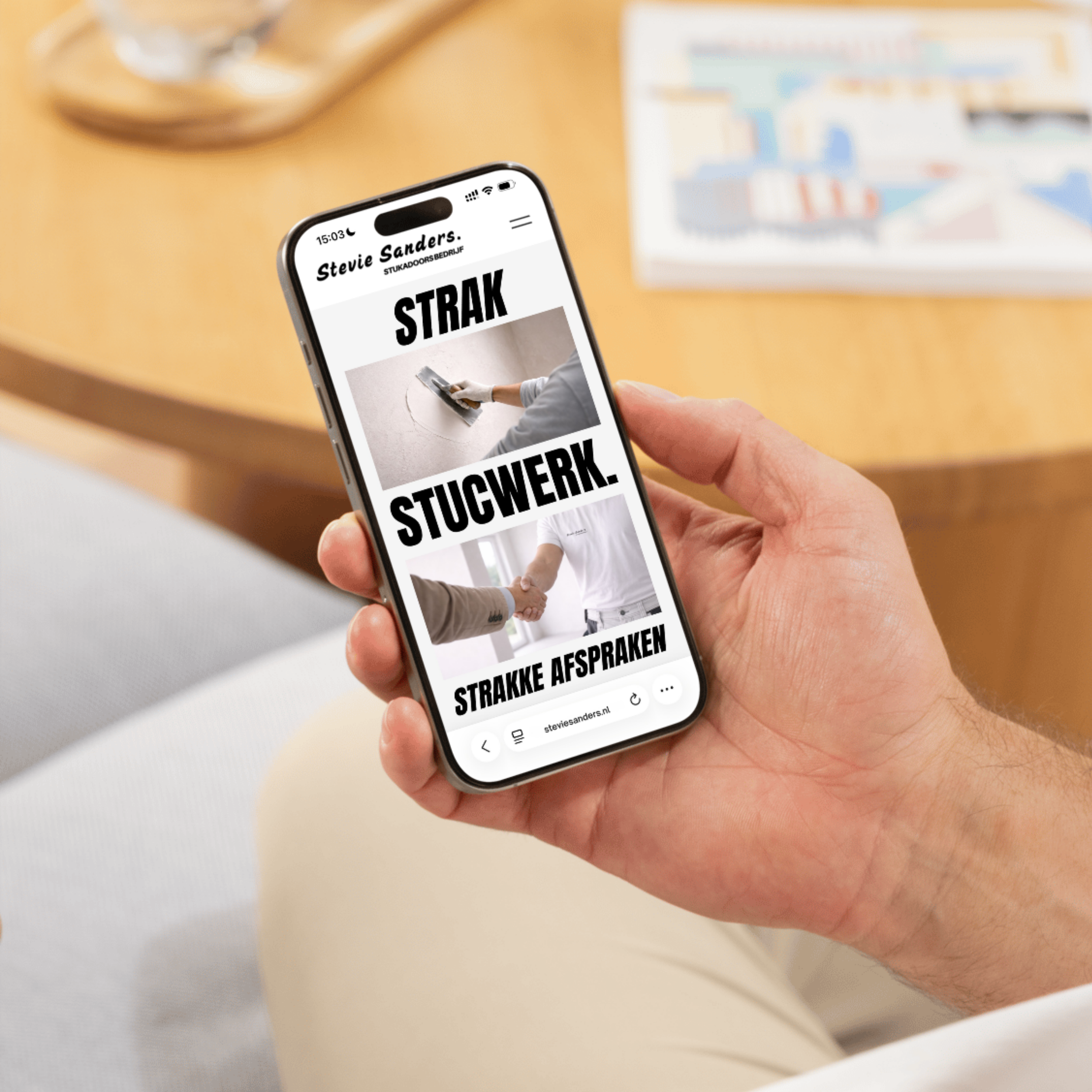 A person holding a smartphone displaying a website with bold black text and images related to handshake agreements on a light-colored wooden table.