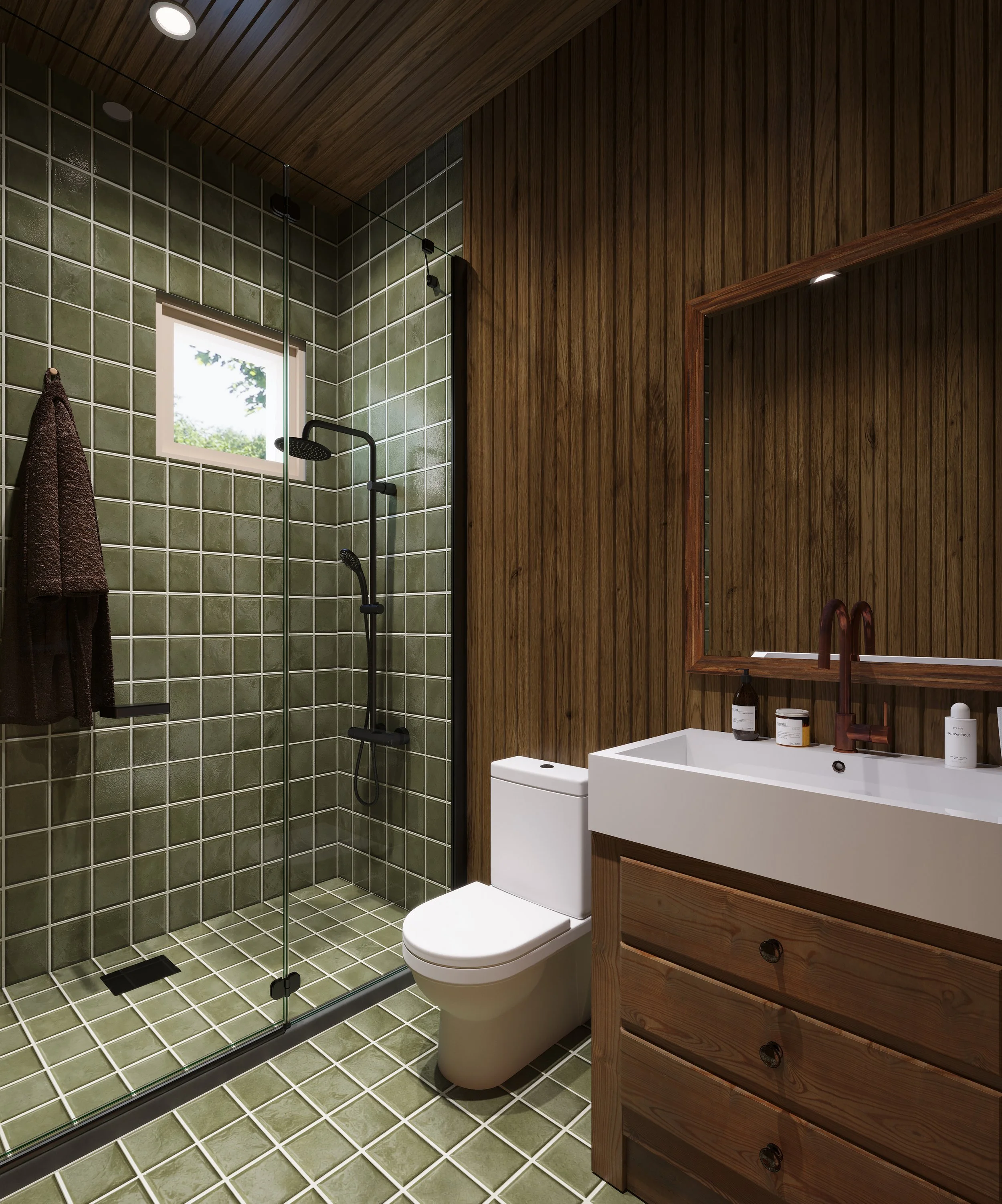 Modern bathroom with green tiled shower area, glass shower door, white toilet, wooden vanity with a sink, mirror, and toiletries.