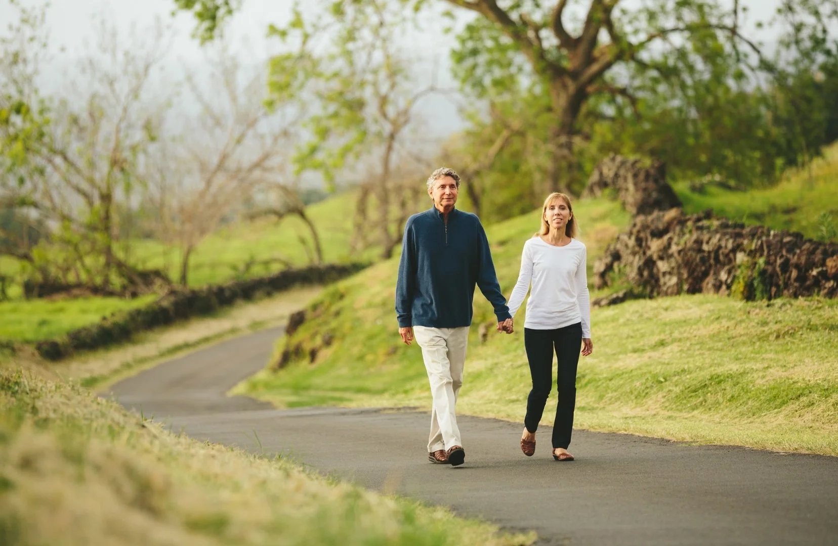 A couple holding hands while enjoying a walk in the nature.