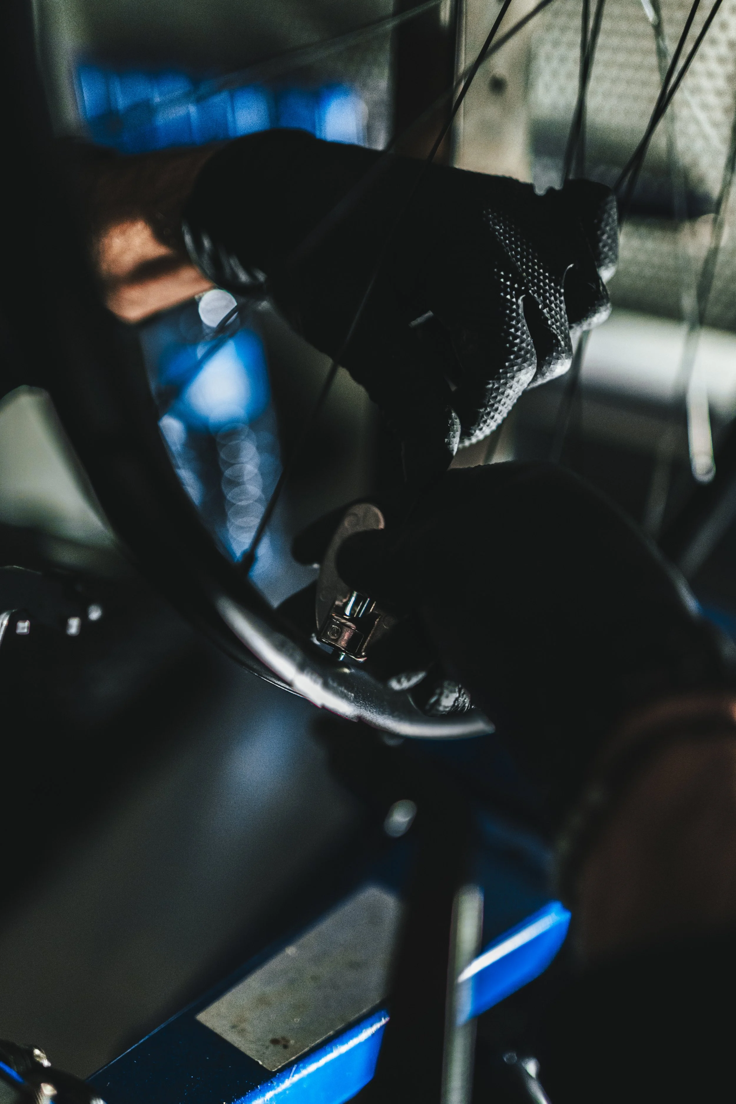 Una mano con guanto nero utilizza un attrezzo per lavorare su una superficie nera, con cavi in vista e luci blu sullo sfondo.