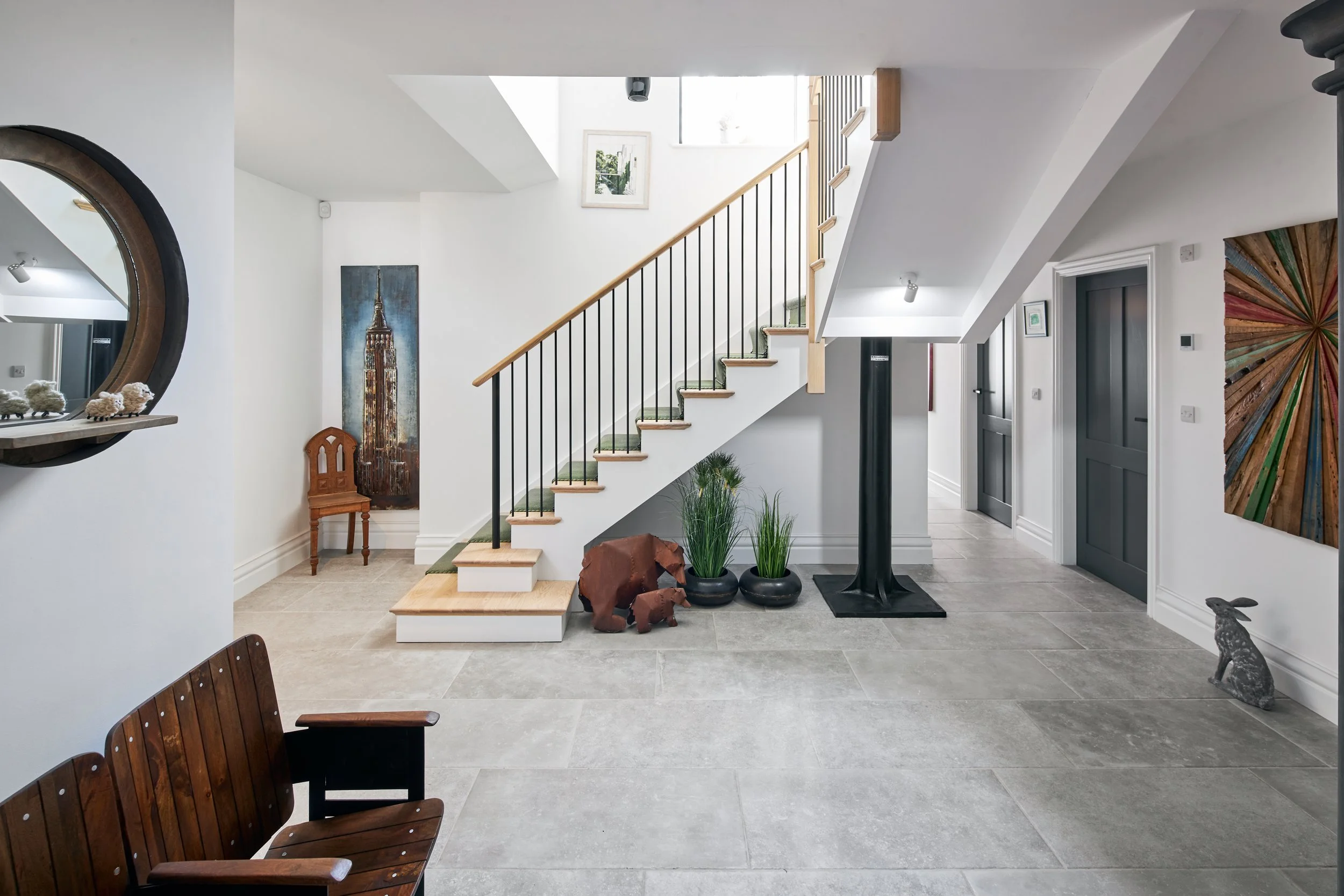 Interior of a modern home with a staircase, potted plants, and artwork on the walls.