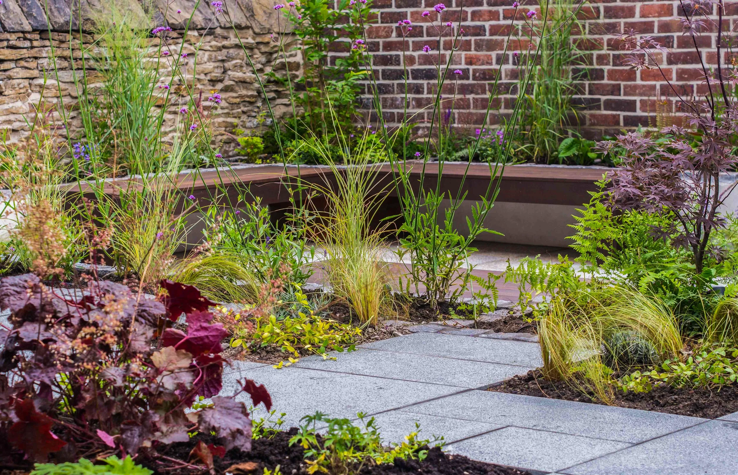 Brown, wooden bench in the Chic garden surrounded by soft planting