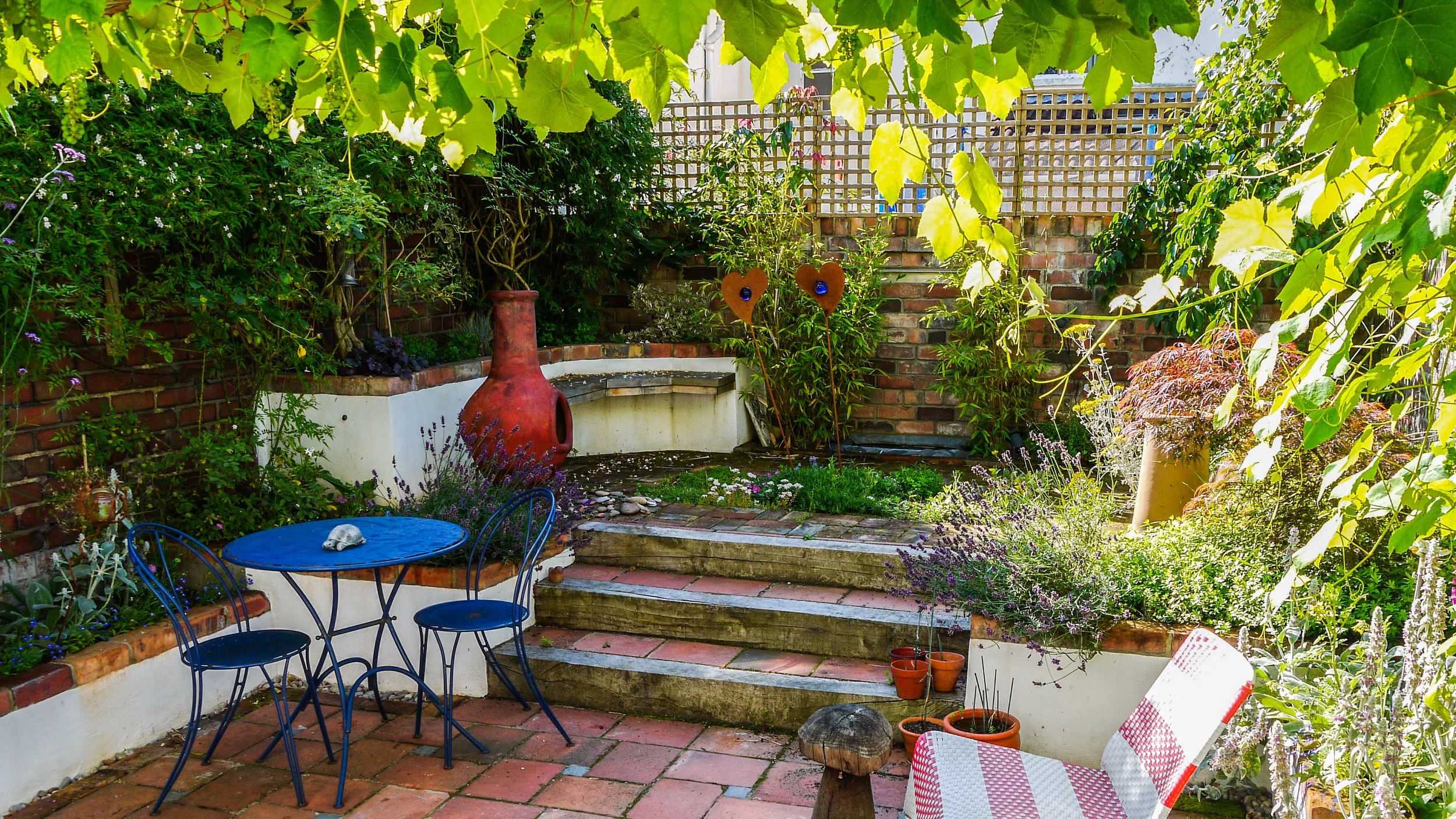 A image of an idyllic and relaxing garden with upcycled materials and lush planting. 