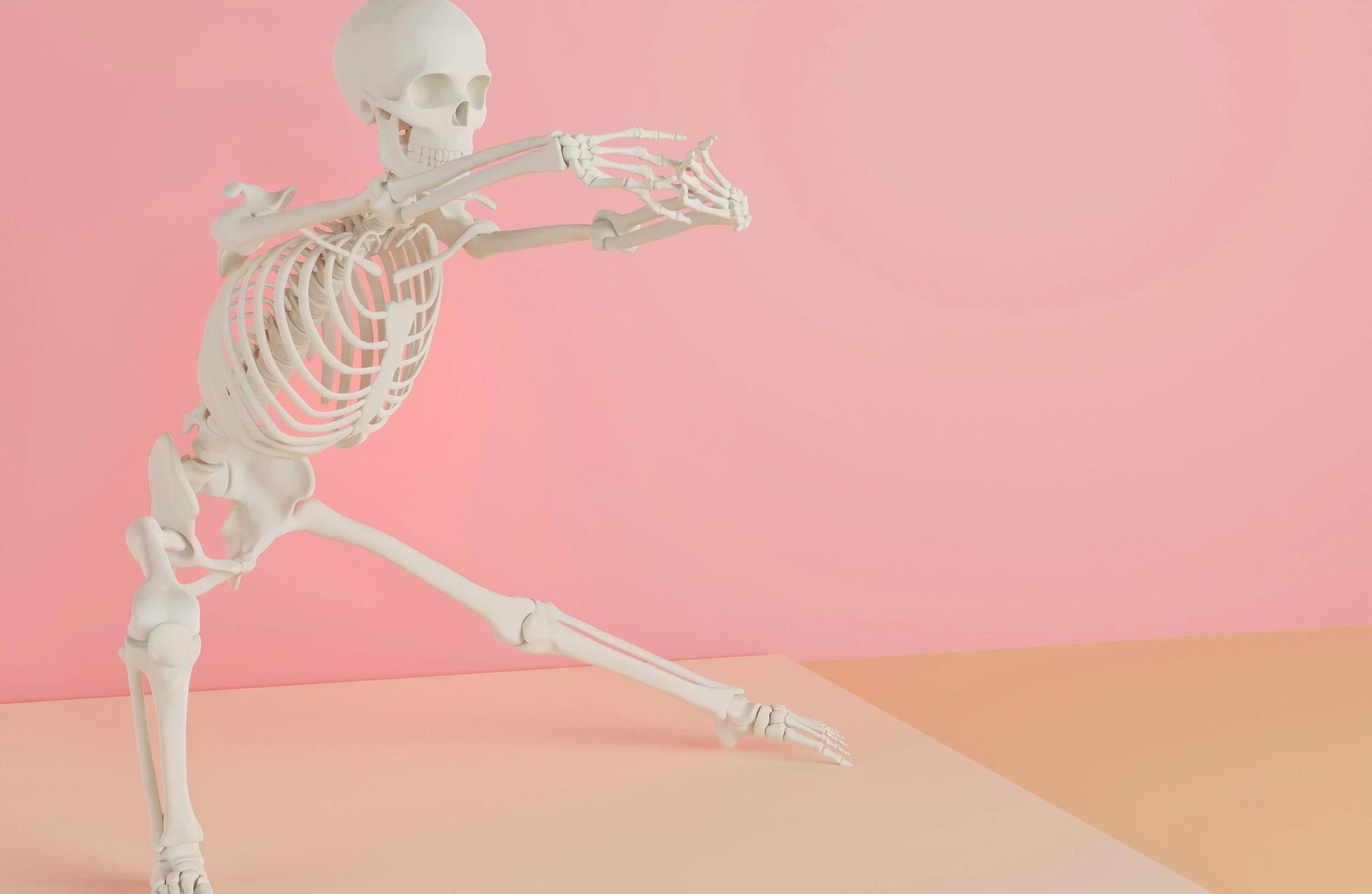 A human skeleton posed as if doing a yoga stretch against a pink background.