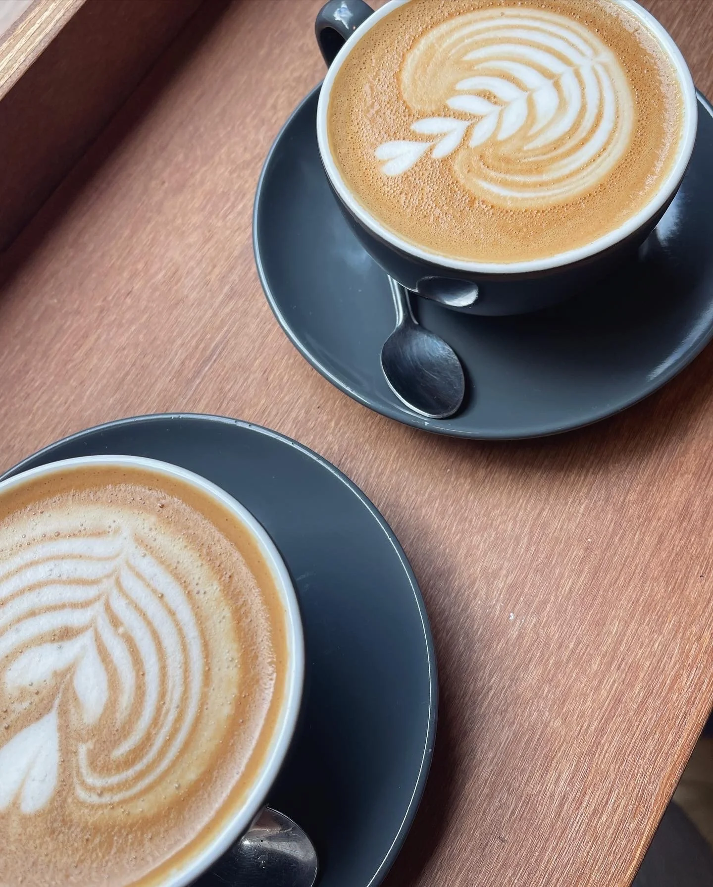 Hands flipping through a sketchbook on a wooden table with various textured material samples and small dishes.