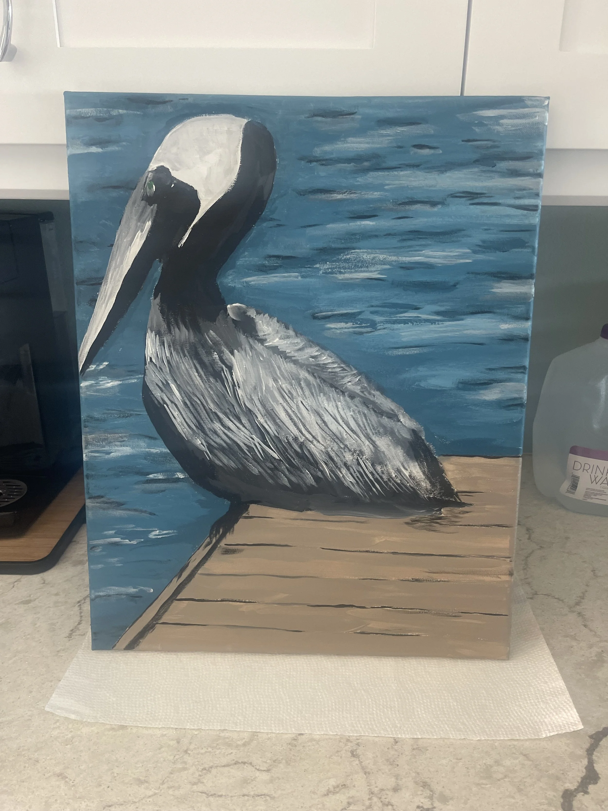 A painted picture of a pelican standing on a wooden dock with water in the background.