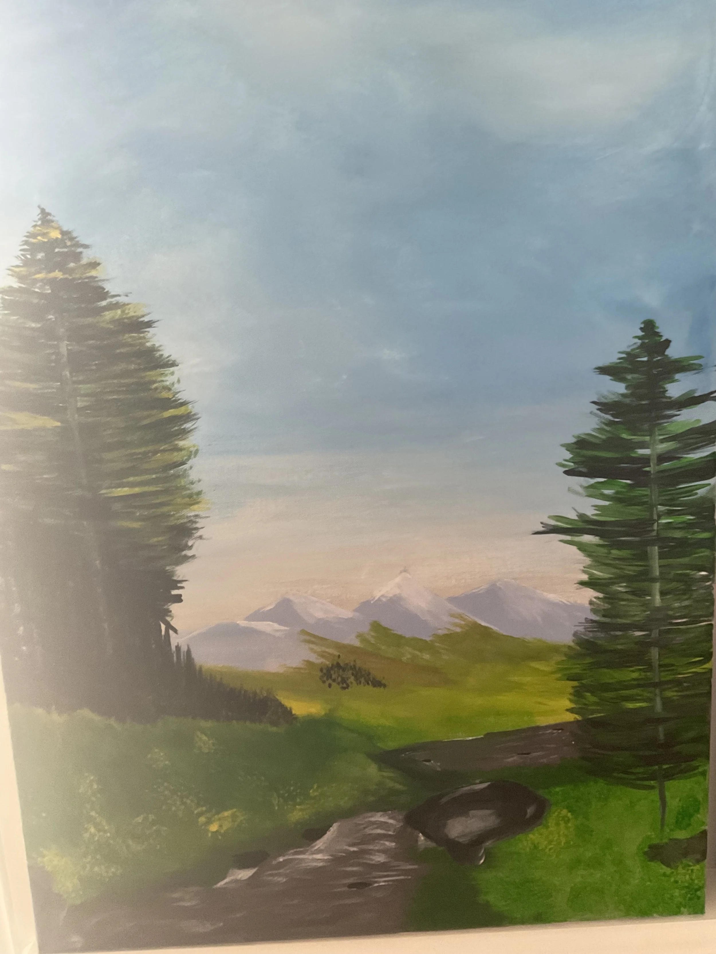 A landscape painting featuring a blue sky, distant snow-capped mountains, tall evergreen trees, green grass, and rocks in the foreground.