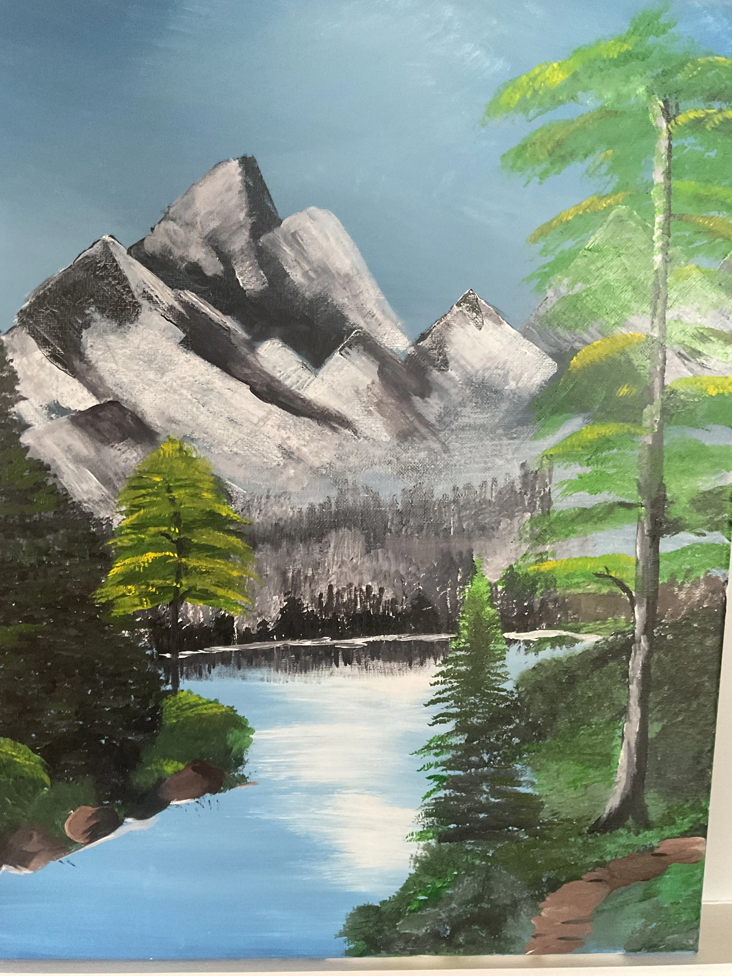 Painting of a mountain landscape with tall, rugged peaks, a calm lake reflecting the sky, and green trees in the foreground.