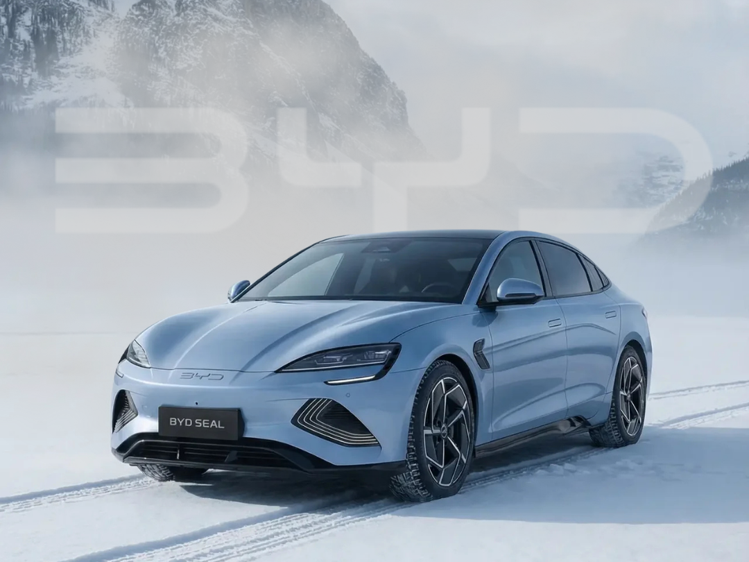 A light blue BYD Seal electric car on snow in a mountainous landscape.