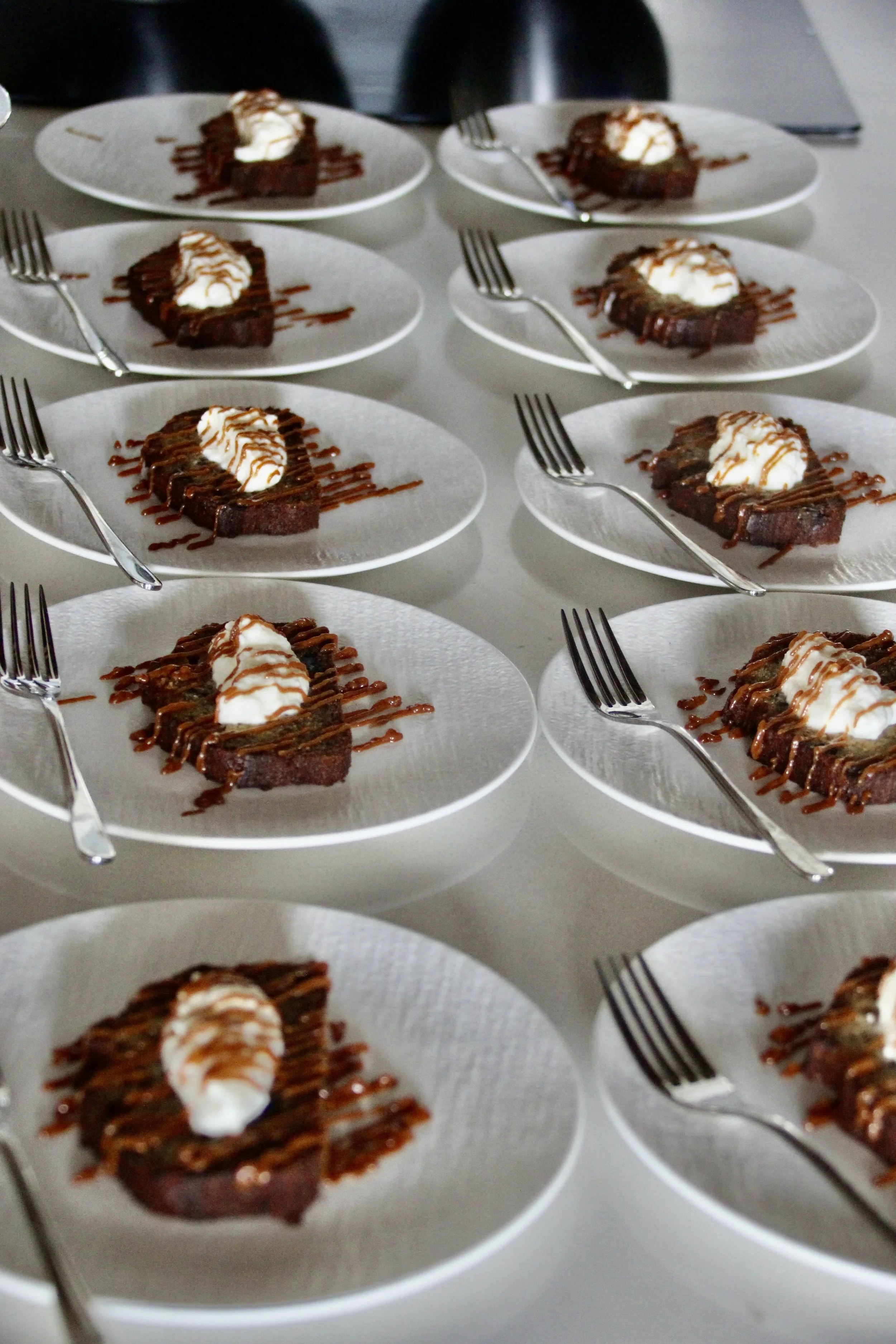 plats de gâteau au chocolat avec de la crème chantilly et du caramel, accompagnés de fourchettes, sur des assiettes blanches