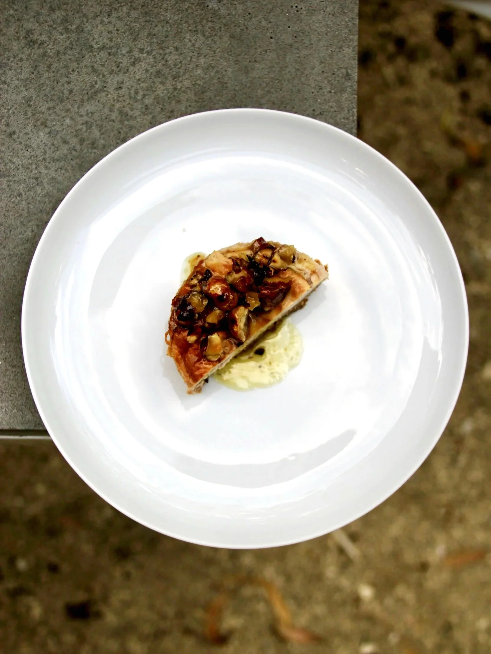 Une assiette de poisson avec une sauce ou un accompagnement de légumes finement hachés sur le dessus, partiellement posé sur une sauce crémeuse, vue de dessus.