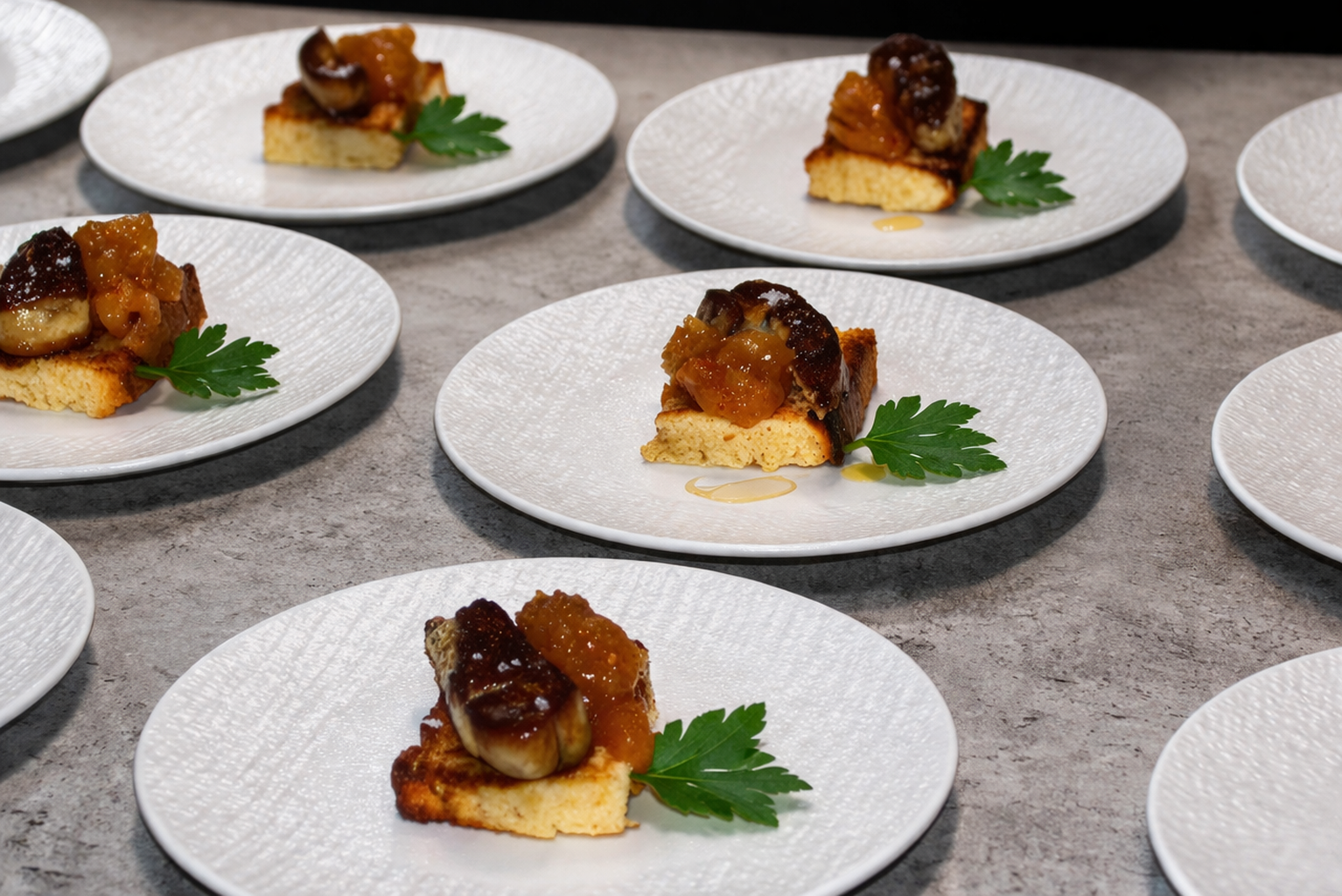 Tartelettes aux figues garnies de compote de figues, avec une feuille de persil en garniture, présentées sur des assiettes blanches.