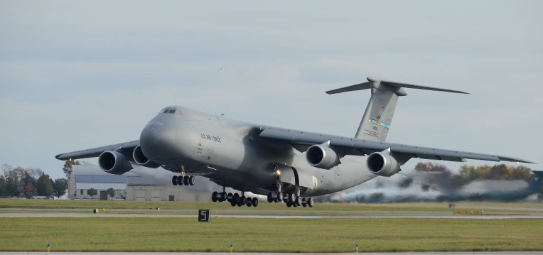 A large military cargo airplane taking off from an airport runway.