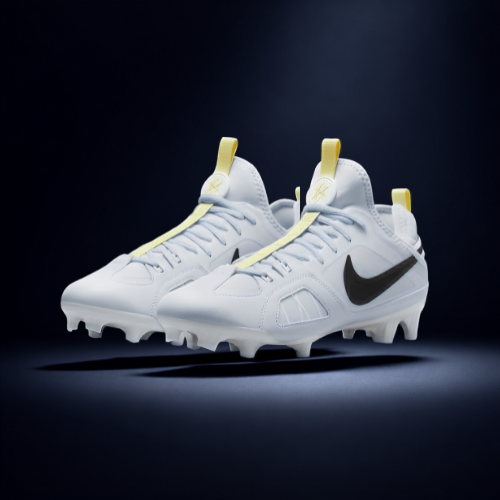 A pair of white athletic cleats with black Nike swoosh logos and yellow accents, displayed against a dark background.