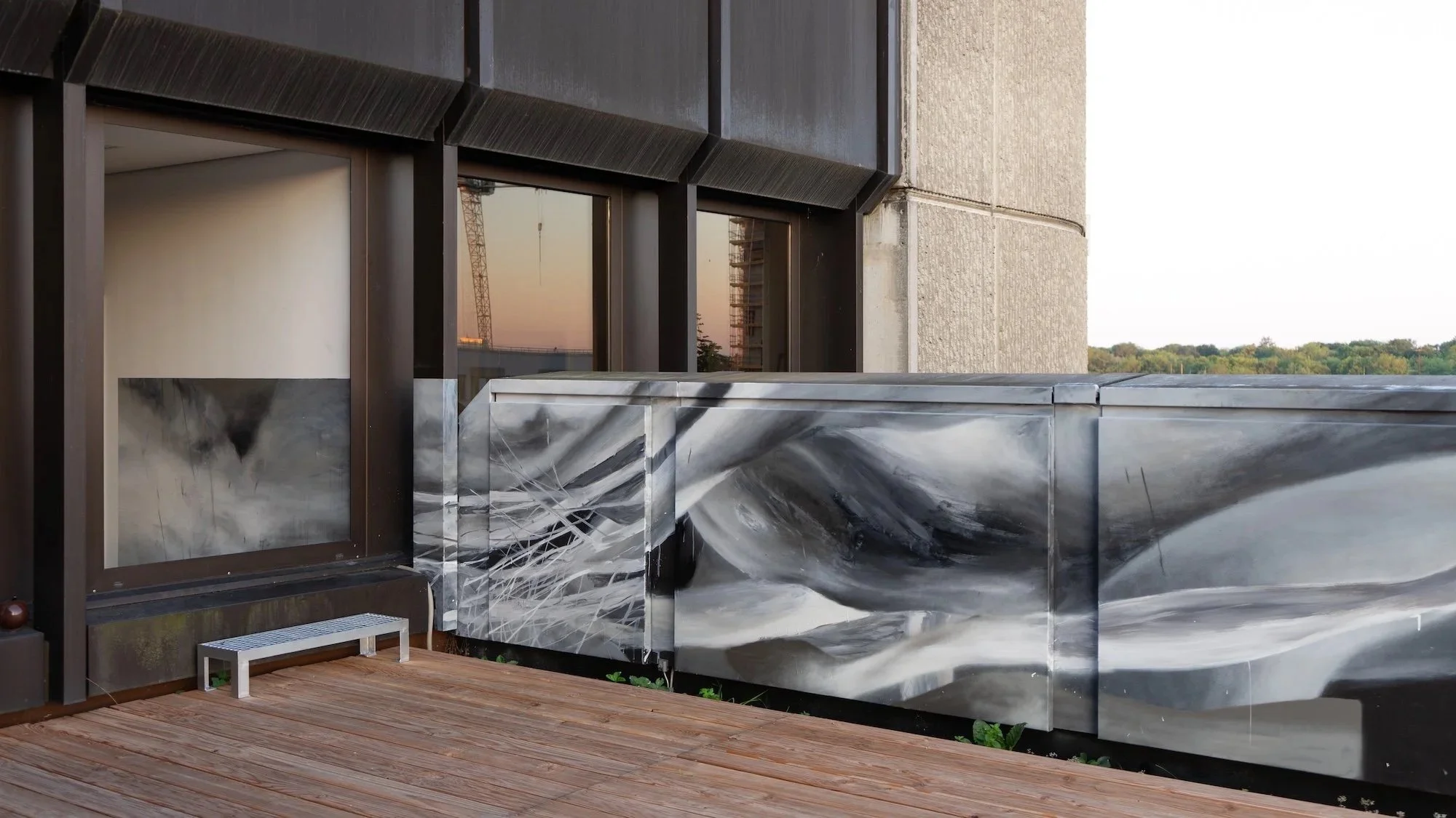 Balkon mit Holzbelag und künstlerischem schwarzen, weißen und grauen Marmor-Design an der Brüstung, Blick auf einen Sonnenuntergang im Hintergrund