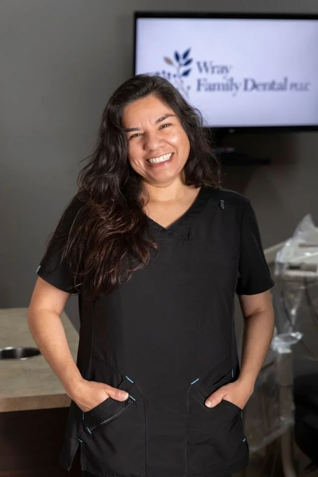 Smiling woman in black scrubs standing in dental office