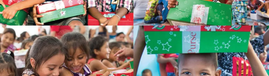 Children holding and smiling at Christmas gift boxes during a festive event.