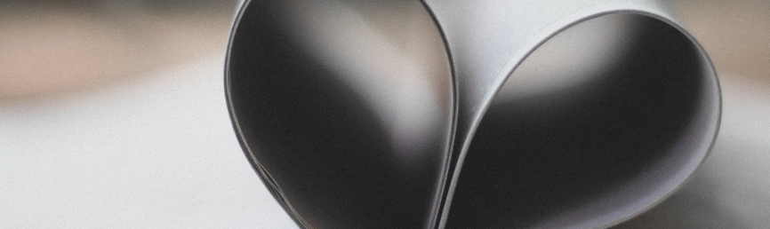 Close-up of a metallic heart-shaped sculpture made from two pieces of curved metal.