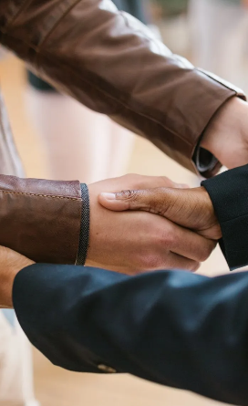 Two people shaking hands, one wearing a brown leather jacket and the other a dark blazer.