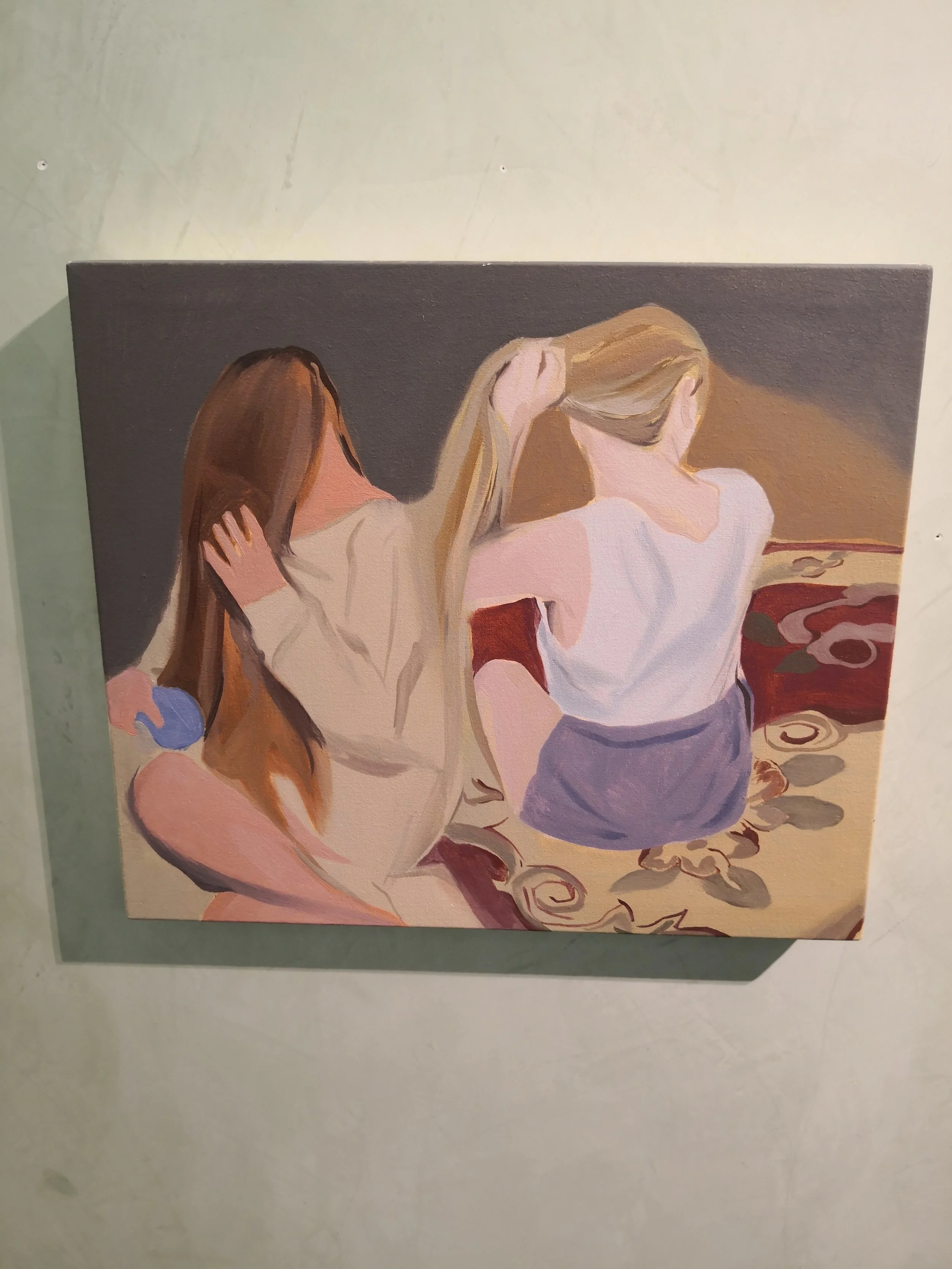 Dipinto di tre donne sedute sul pavimento, con lo sfondo di un tramonto o di una luce calda.