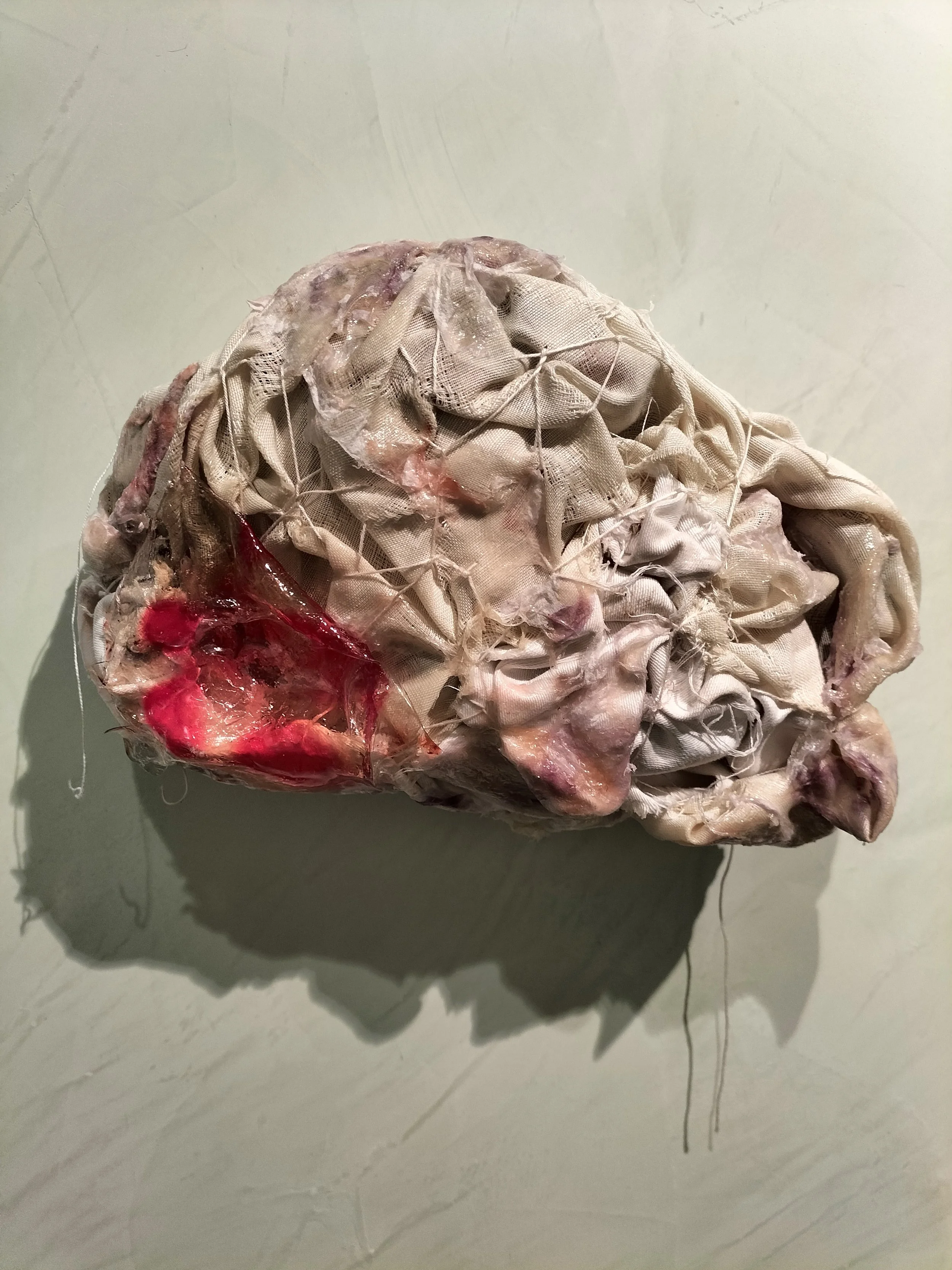 Un oggetto di stoffa sporco e rovinato, con parti rosse e gialle, che sembra un pezzo di tessuto o un'artista concettuale.