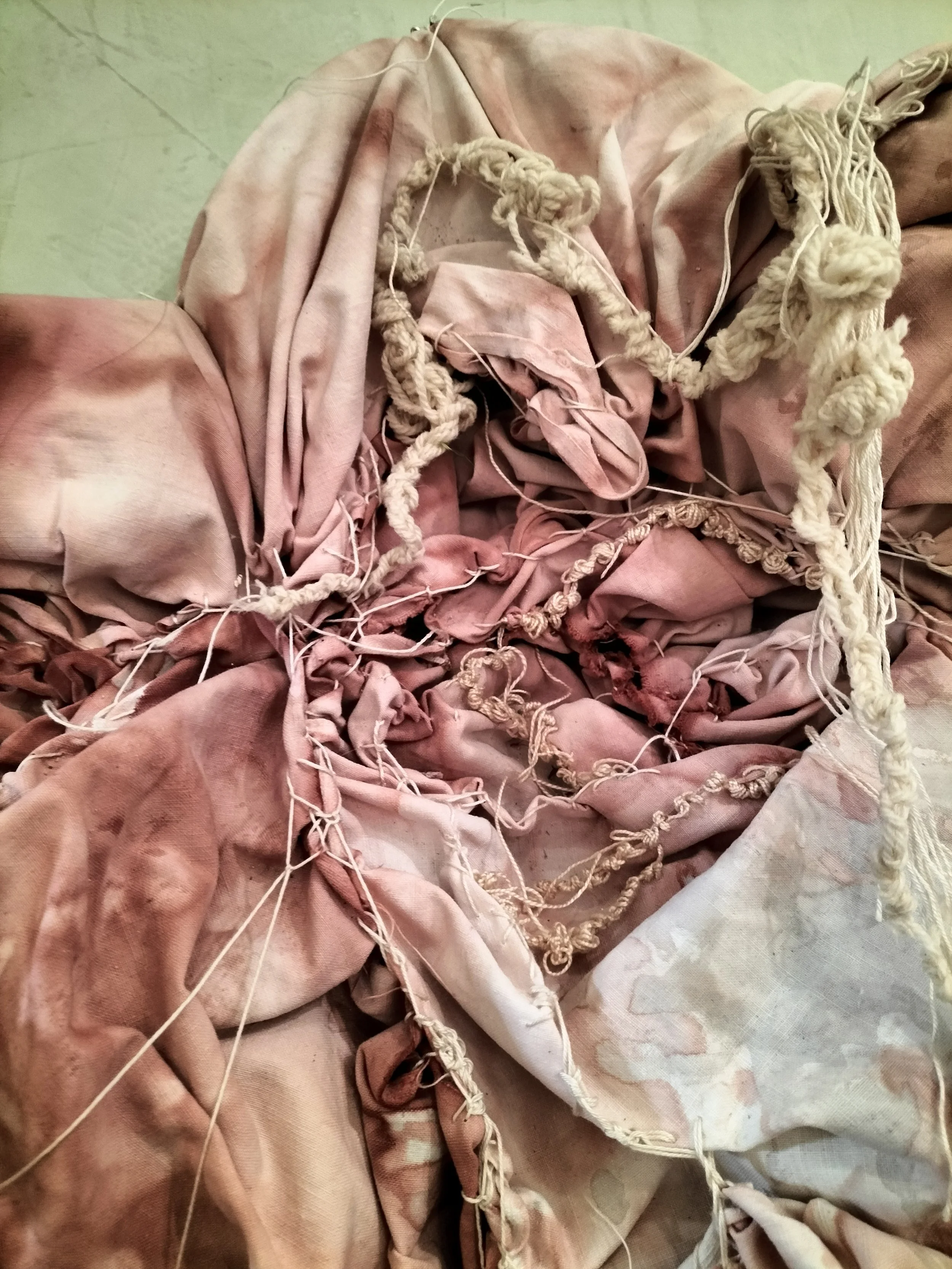 Tessuto rosa stropicciato con fili di cucitura e rotture, parte di una tappezzeria o di un indumento.