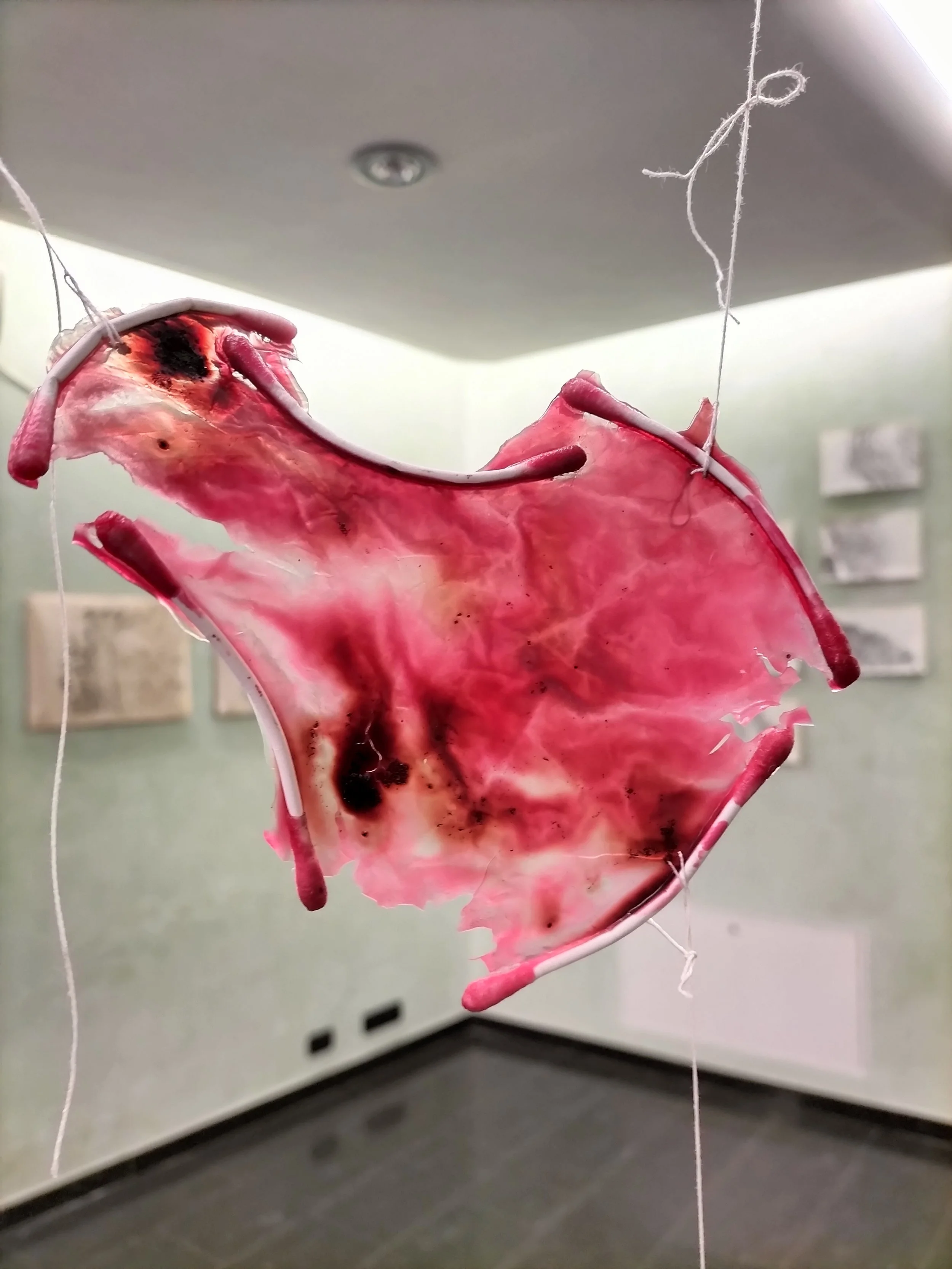 Una crostata di carne disegnata con materiali artistici, sospesa nell'aria, in una galleria o esposizione.