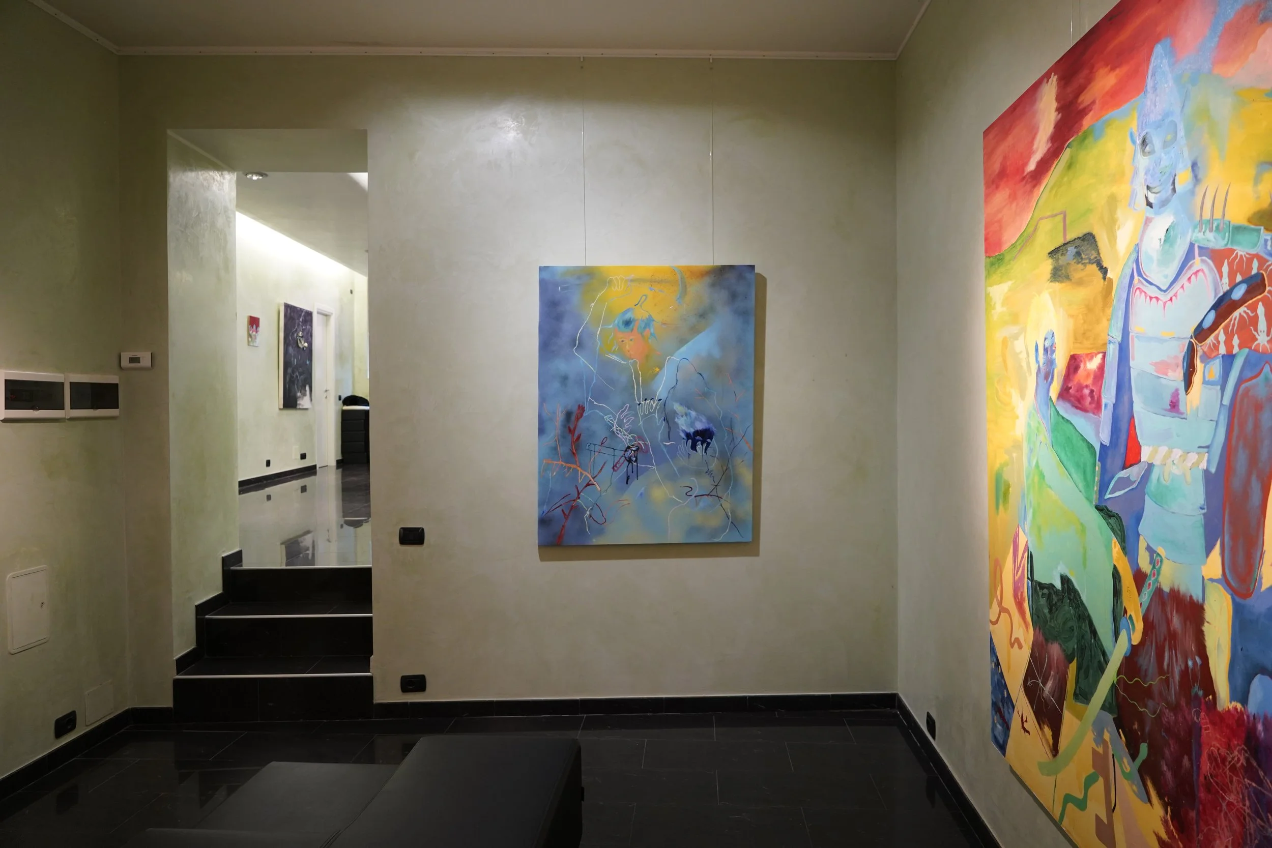 Antiche pareti in stile classico con dipinti moderni e astratti in esposizione, pavimenti in piastrelle nere lucide e scale nere, ambiente di galleria d'arte