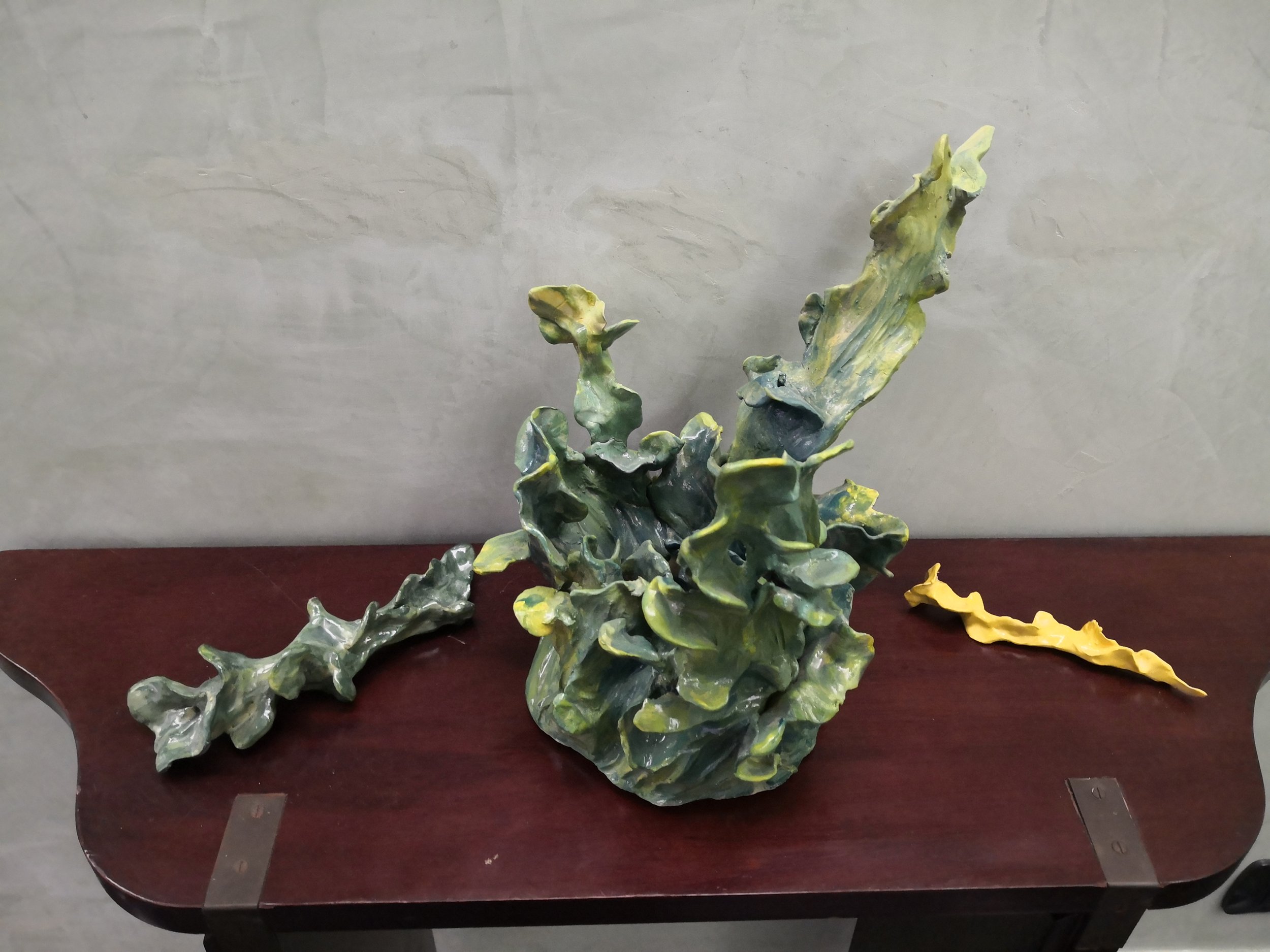 Scultura astratta di foglie di verde e giallo su tavolo di legno.