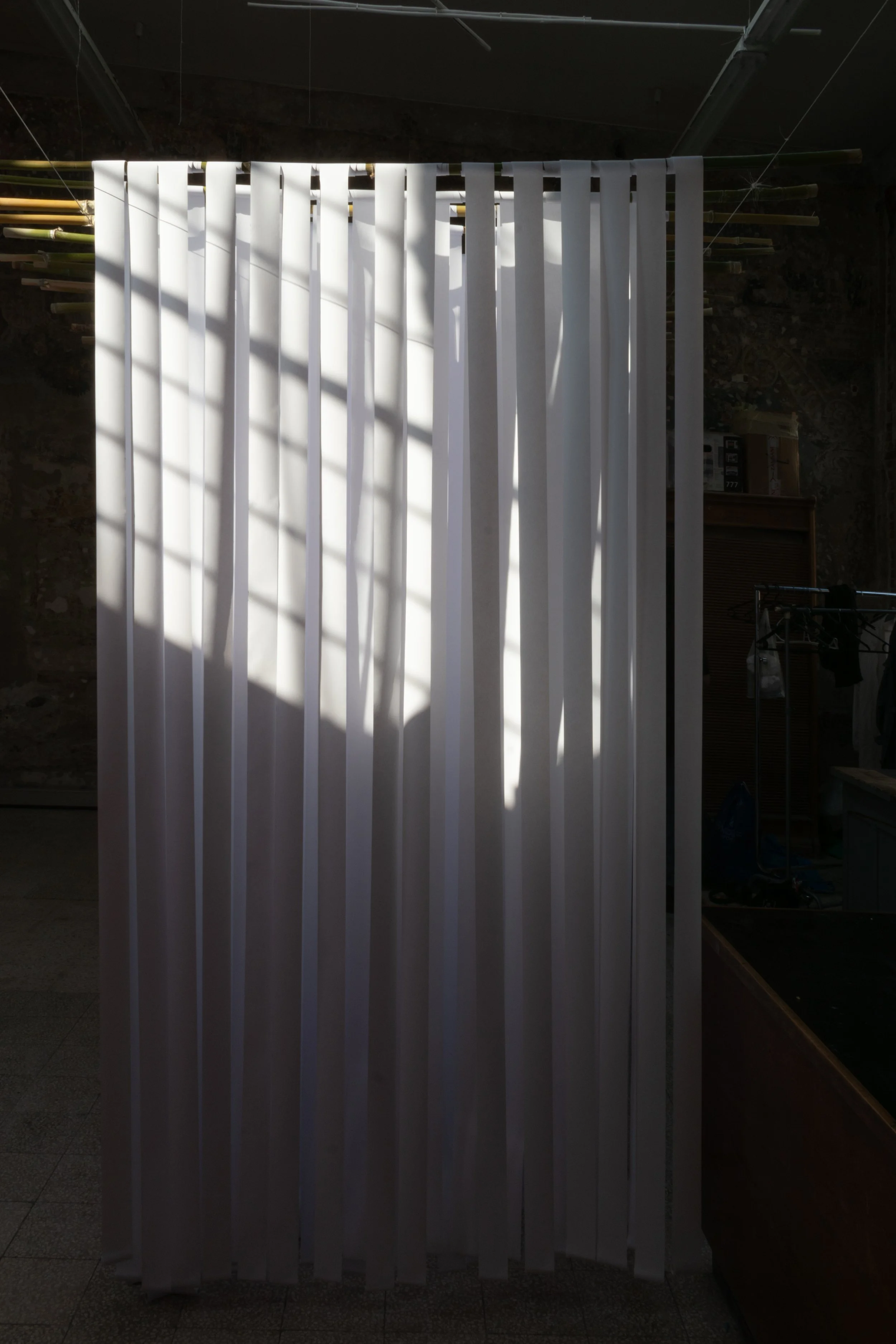 schermo di separazione bianco con fasce verticali, con luci e ombre che creano un motivo a strisce, in un ambiente interno