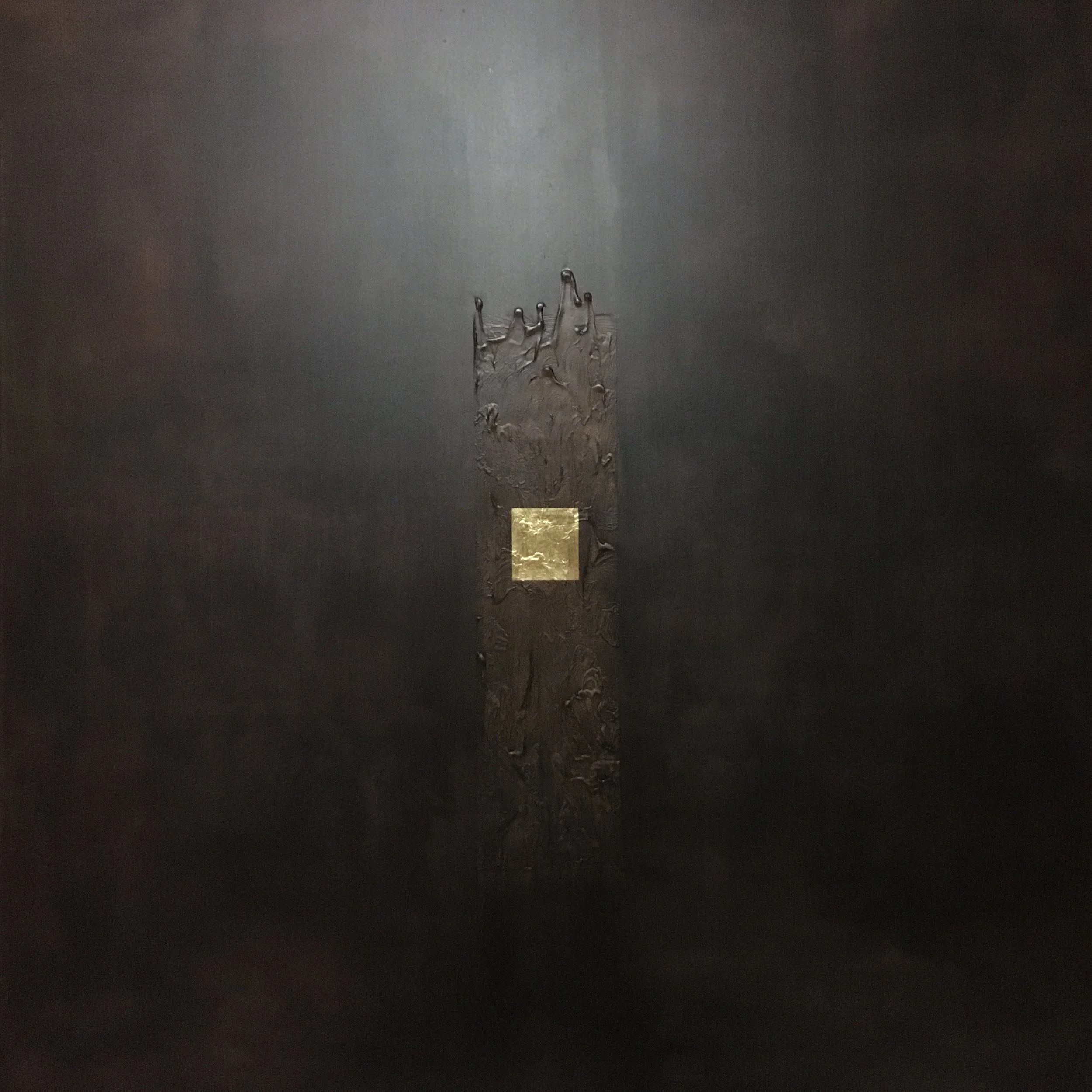 Superficie scura con una striscia centrale di materiale metallico che presenta una placca dorata quadrata