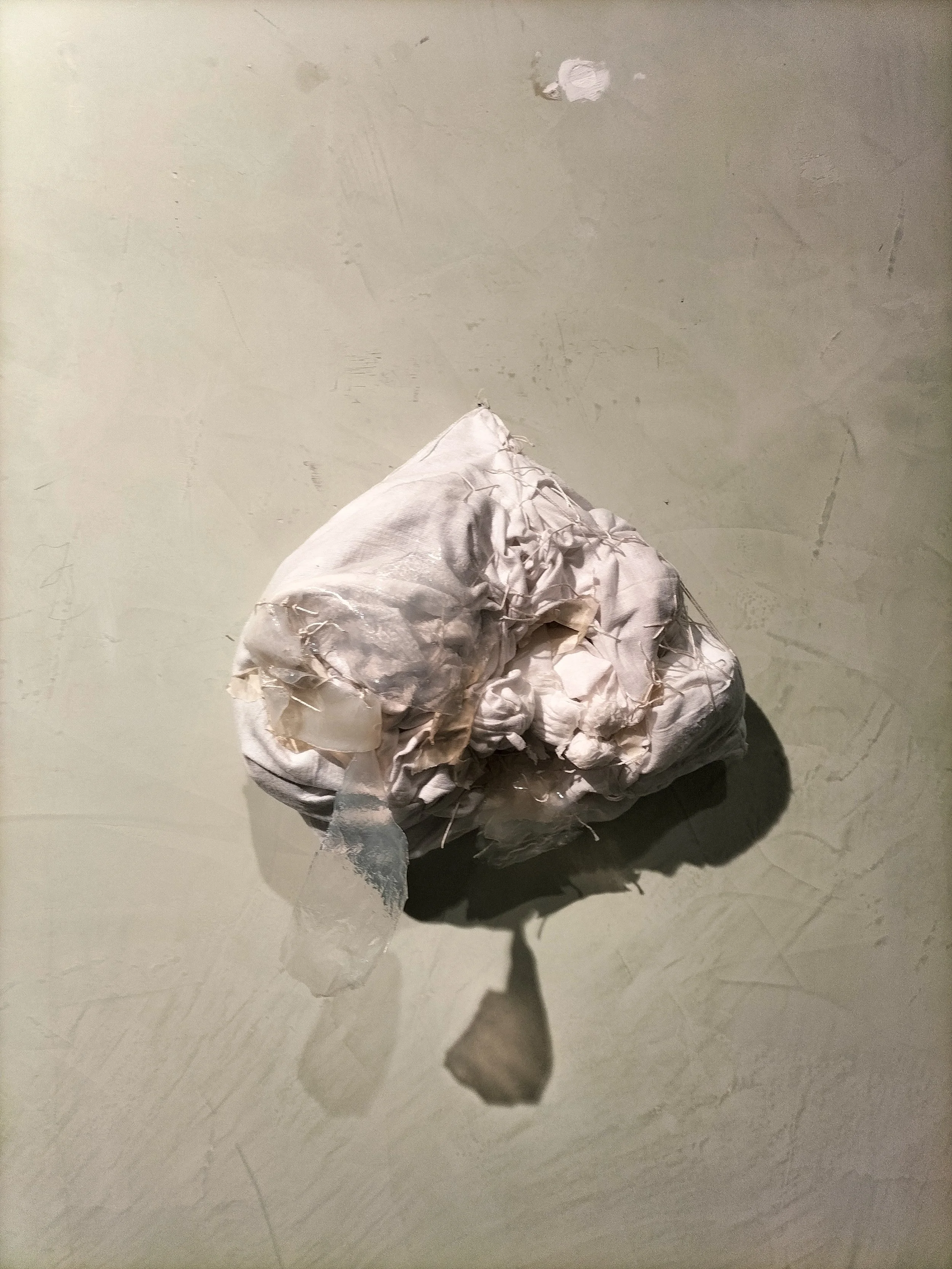 Panno sporco e arruffato con fili e residui di tessuto, appoggiato su una superficie di colore chiaro.