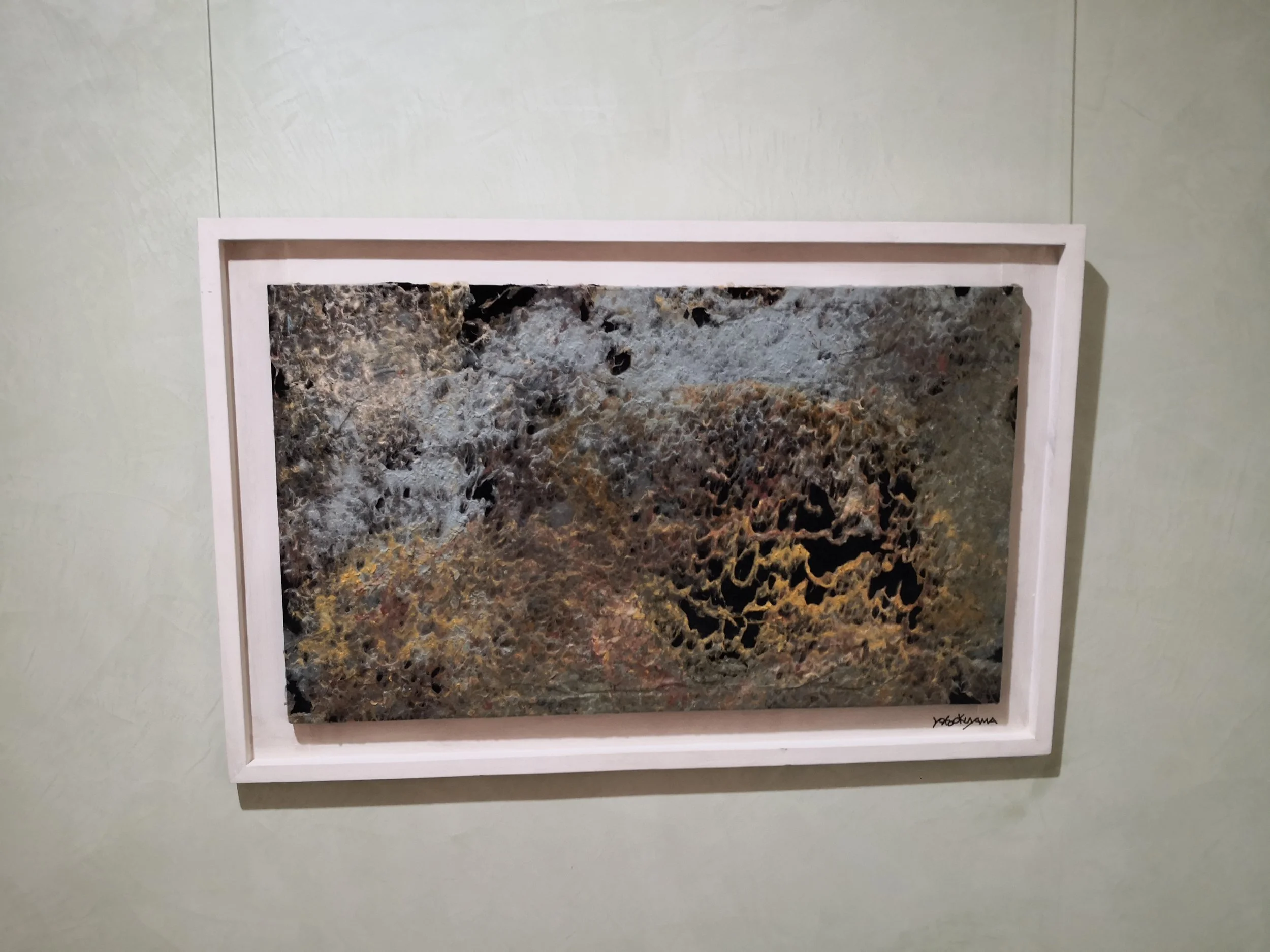 Un quadro astratto con motivi di colore nero, marrone, beige e grigio, firmato dall'artista in basso a destra.