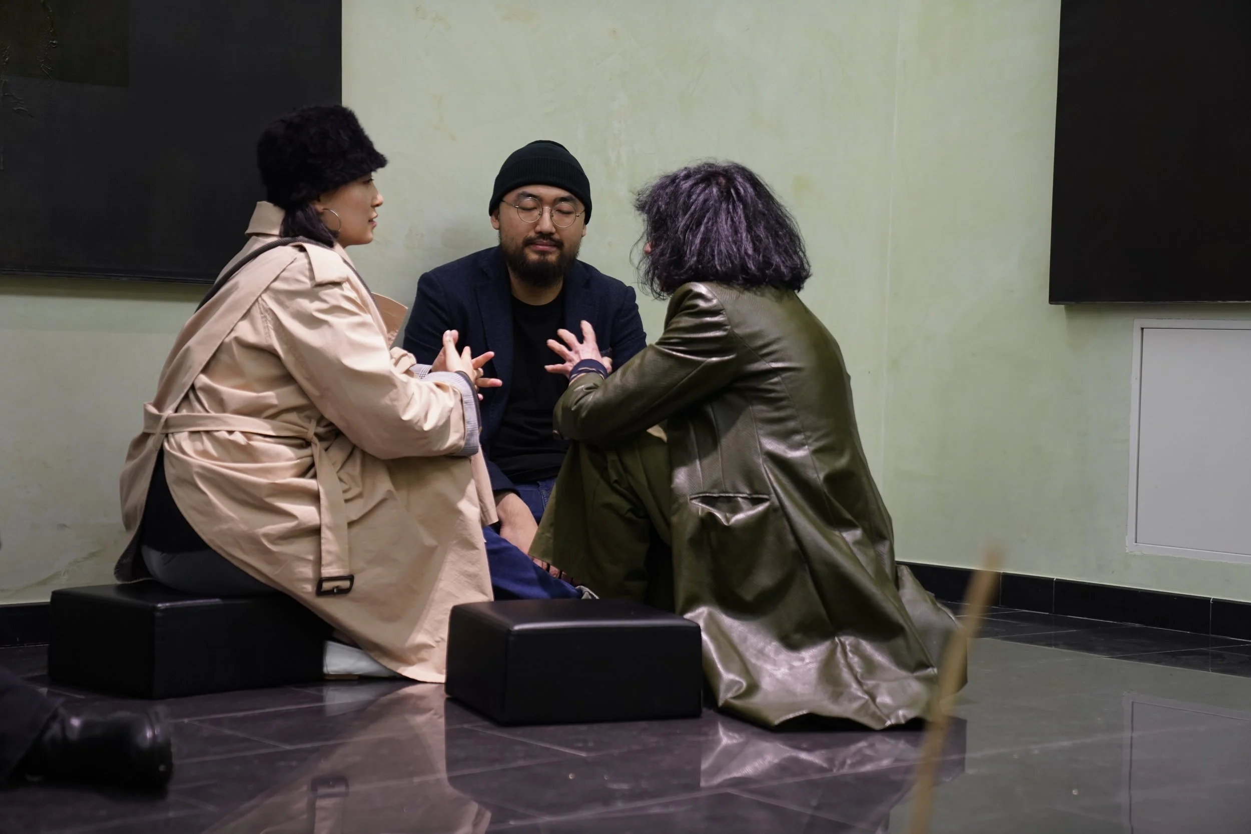 Tre persone sedute a terra che partecipano a una sessione di sostegno o terapia, con una delle persone che pare essere in forte emozione.