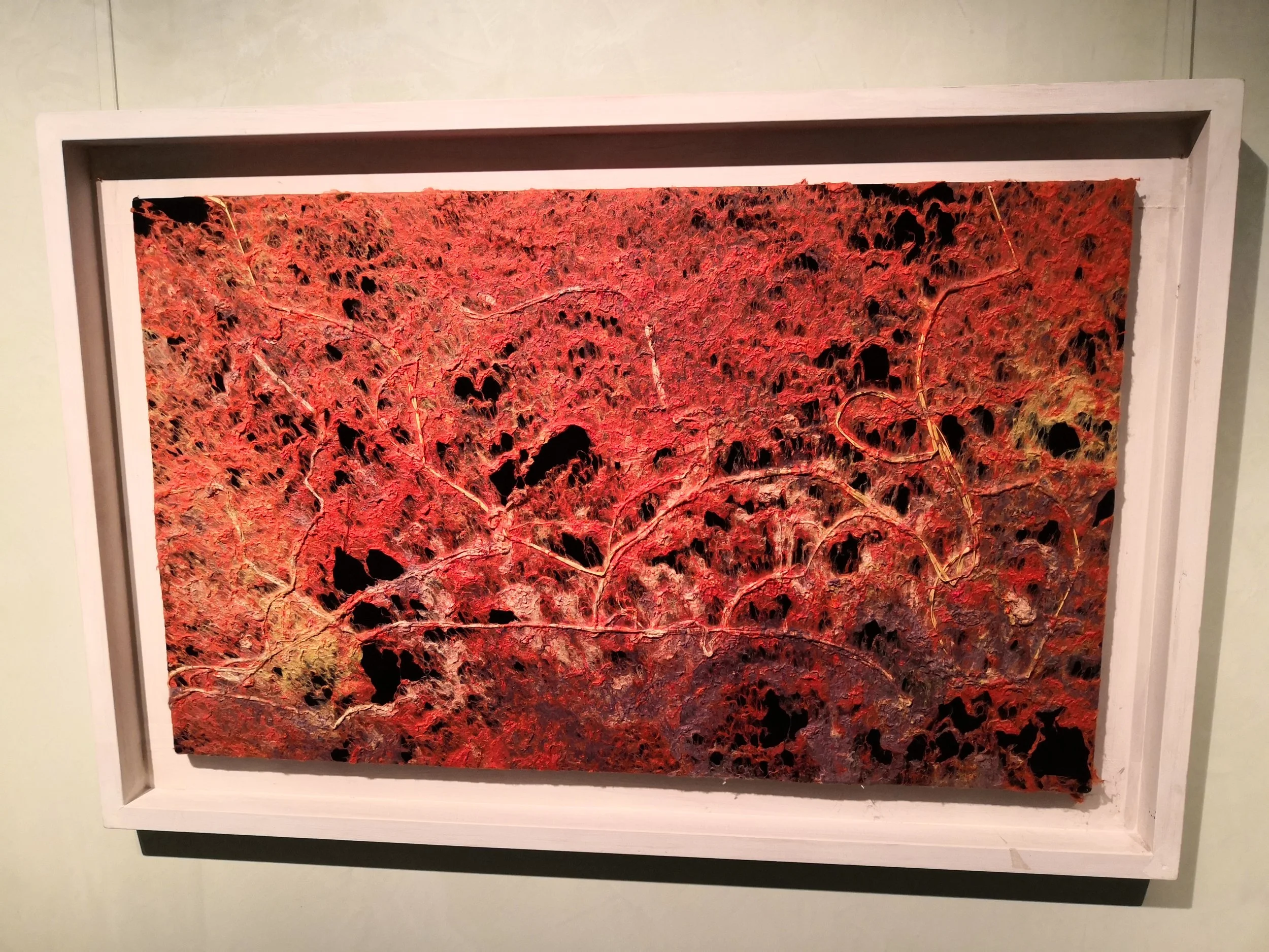 Dipinto astratto con predominanza di rosso e nero, con texture complessa e linee sottili che si intersecano.