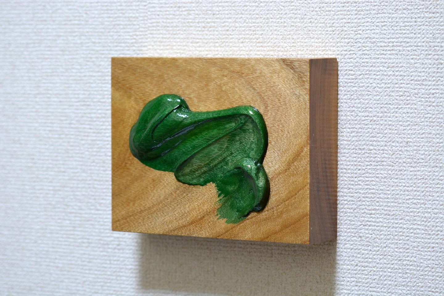 Opera di arte con tinta verde su tavola di legno, rappresentando una foglia