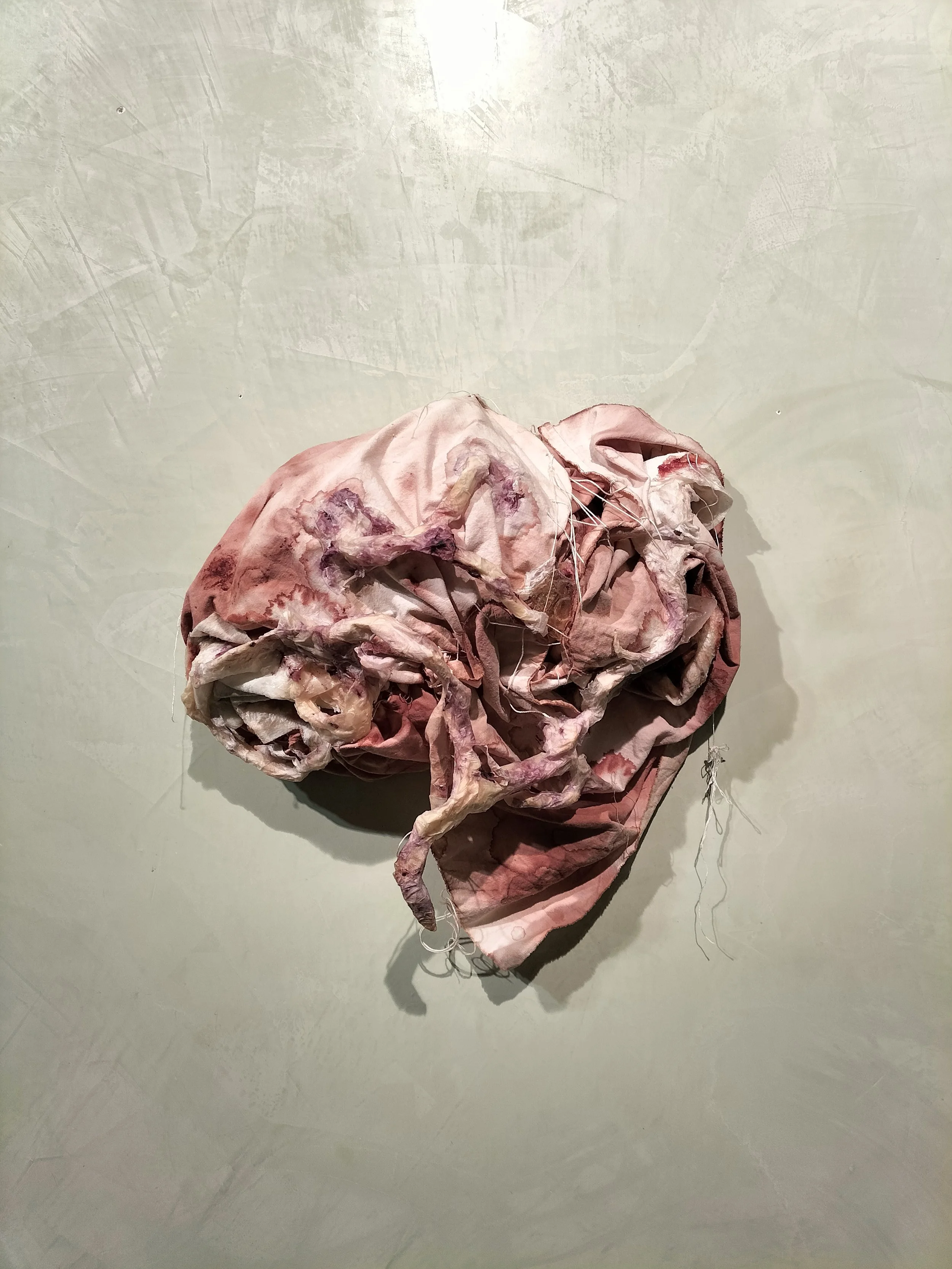 Installazione artistica di tessuti rotti e sgualciti appesi al muro.