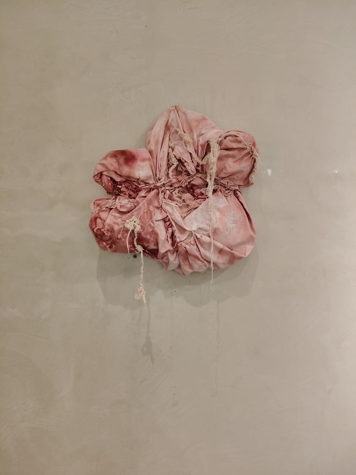 Un tessuto rosa arricciato e sfilacciato appoggiato su una parete
